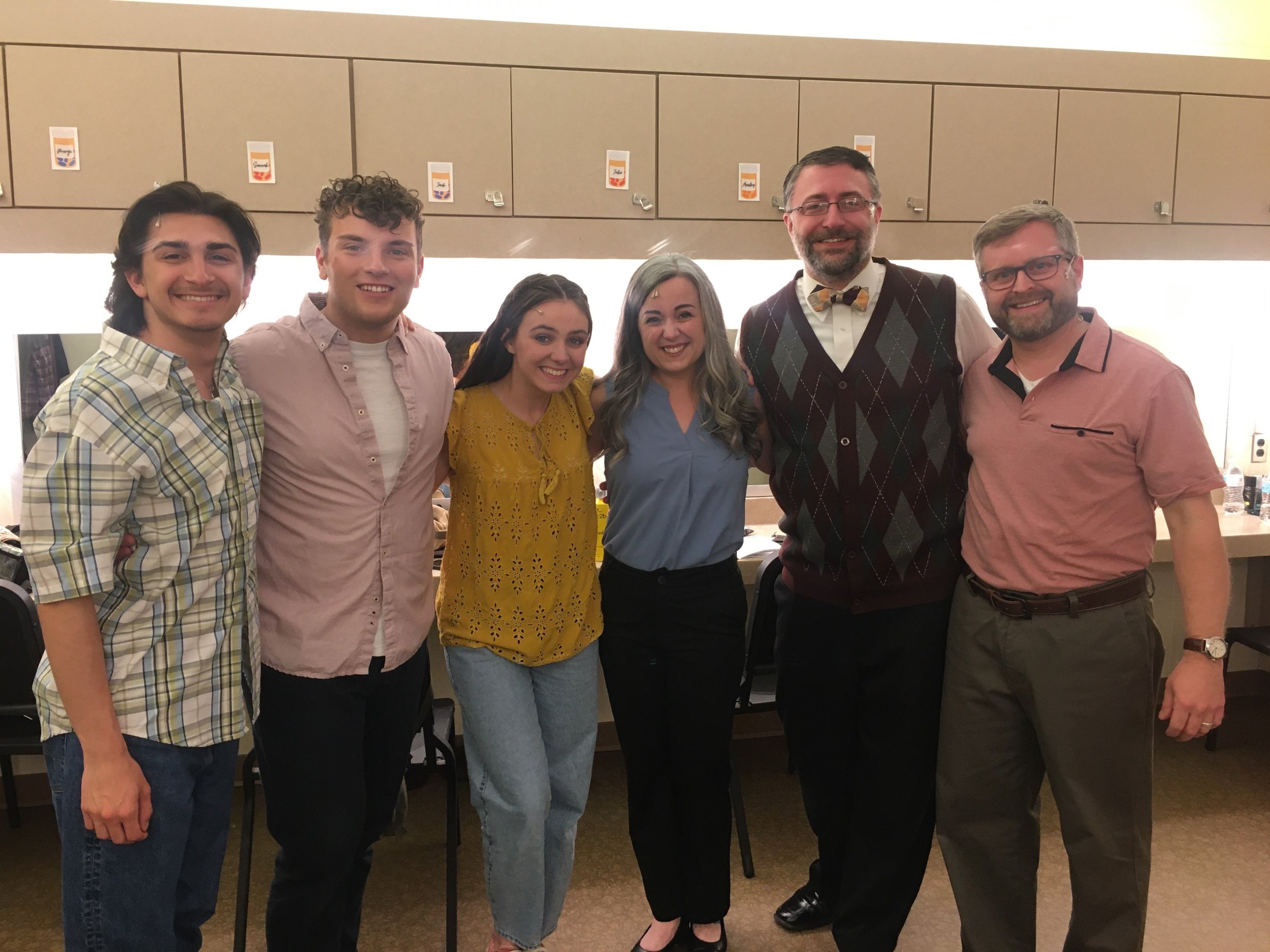 A group of seven people standing together indoors, smiling at the camera.