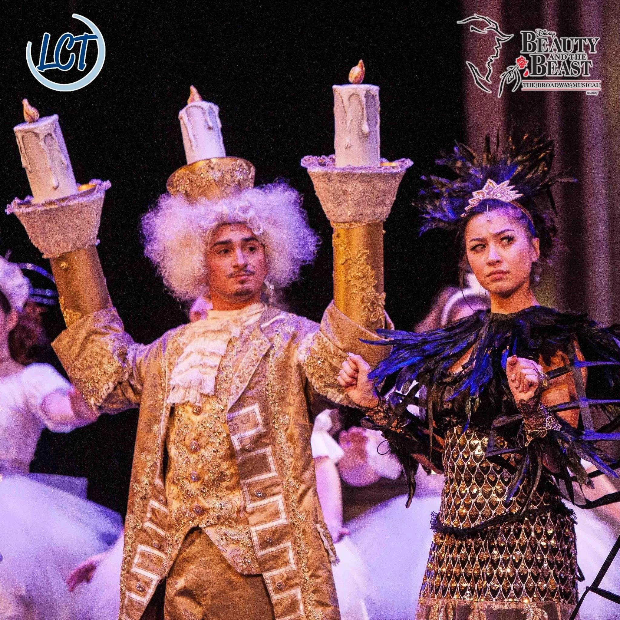 Costumed performers from Disney's 'Beauty and the Beast' musical, with one holding candles and both dressed in elaborate costumes.