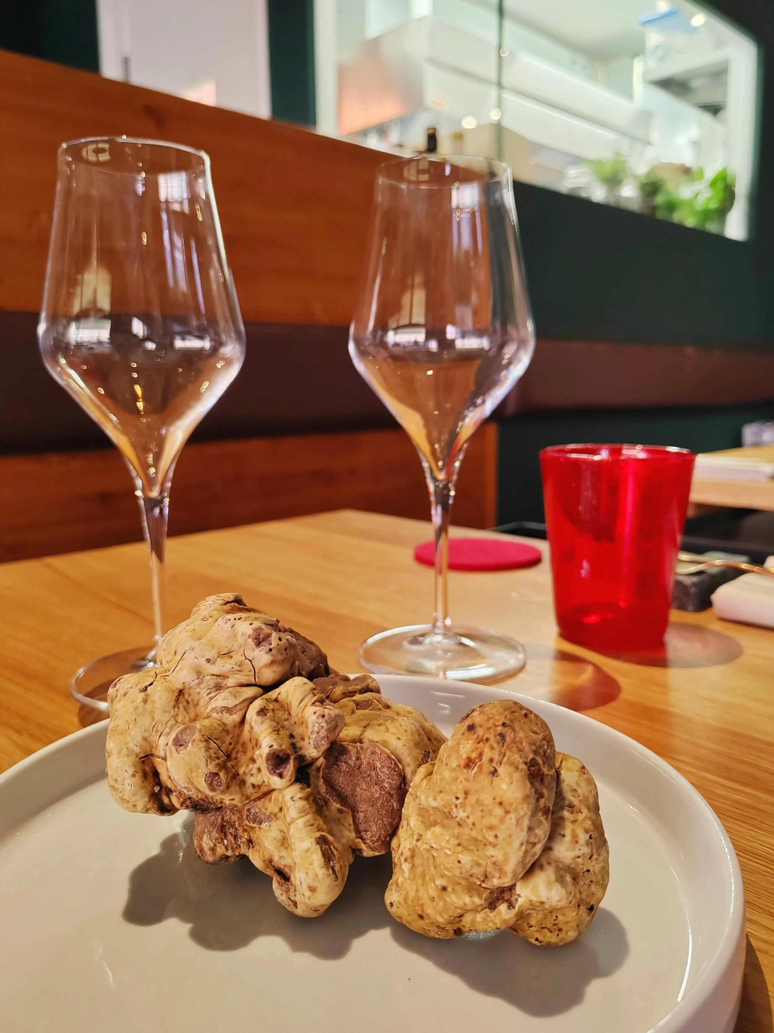 Tartufo bianco d'Alba e due calici di vino vuoti su un tavolo di legno in un ristorante.