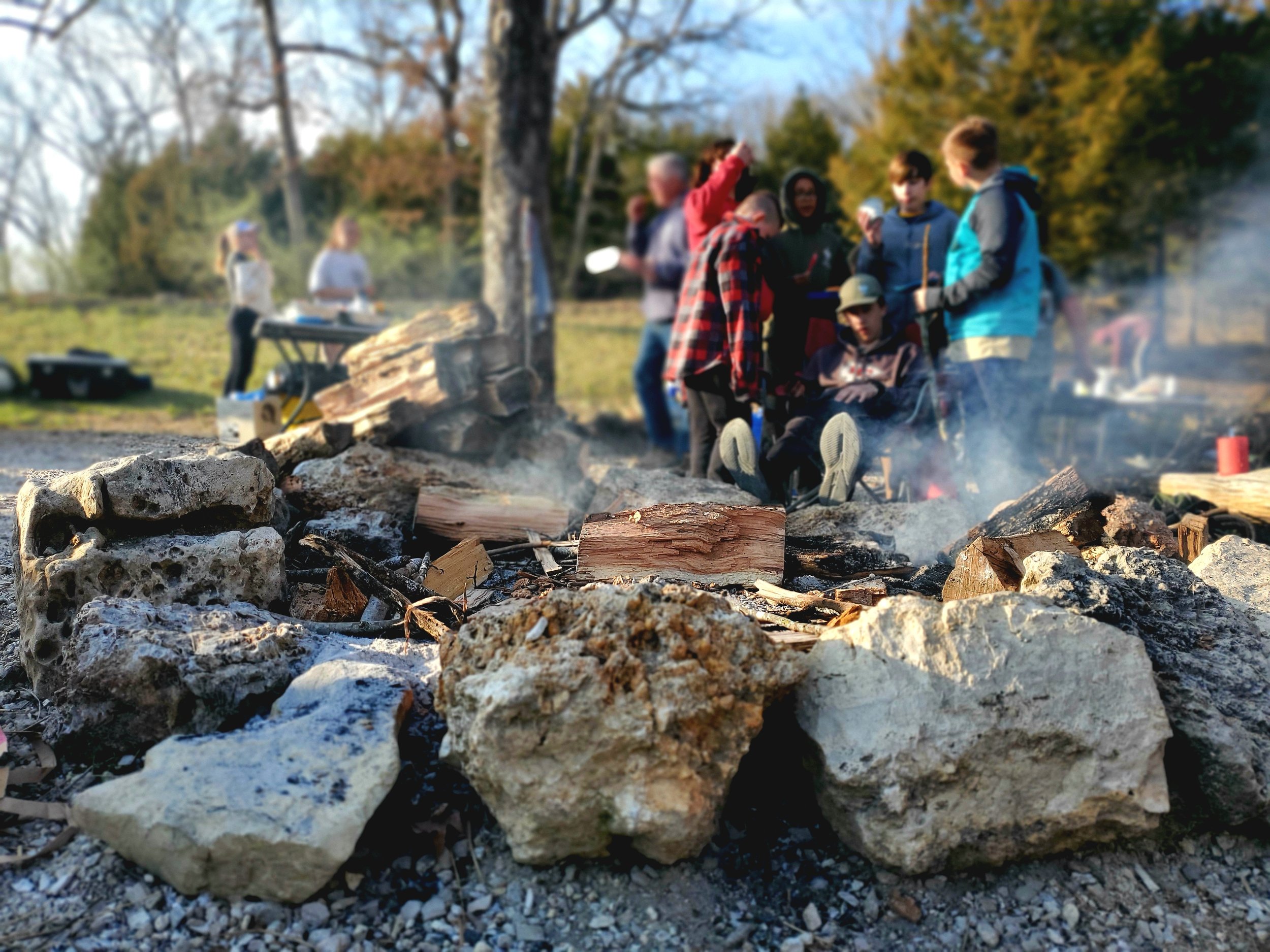 A group of scouts preparing to roast marshmallows while sitting around a campfire
