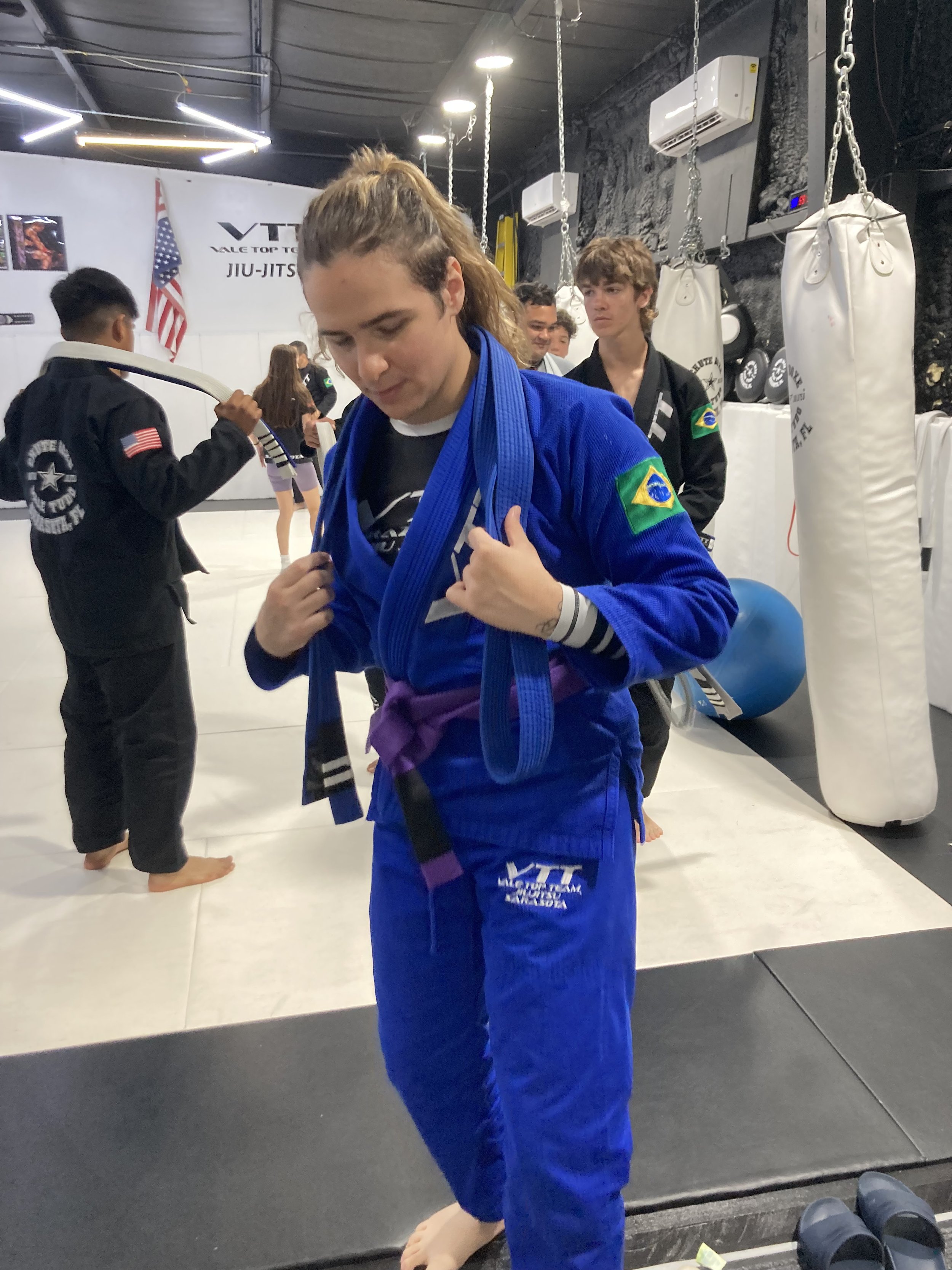 Male runner celebrating on a winners' podium at a marathon event, wearing a medal, sunglasses, and running shorts, with a backdrop displaying the event branding and logos.