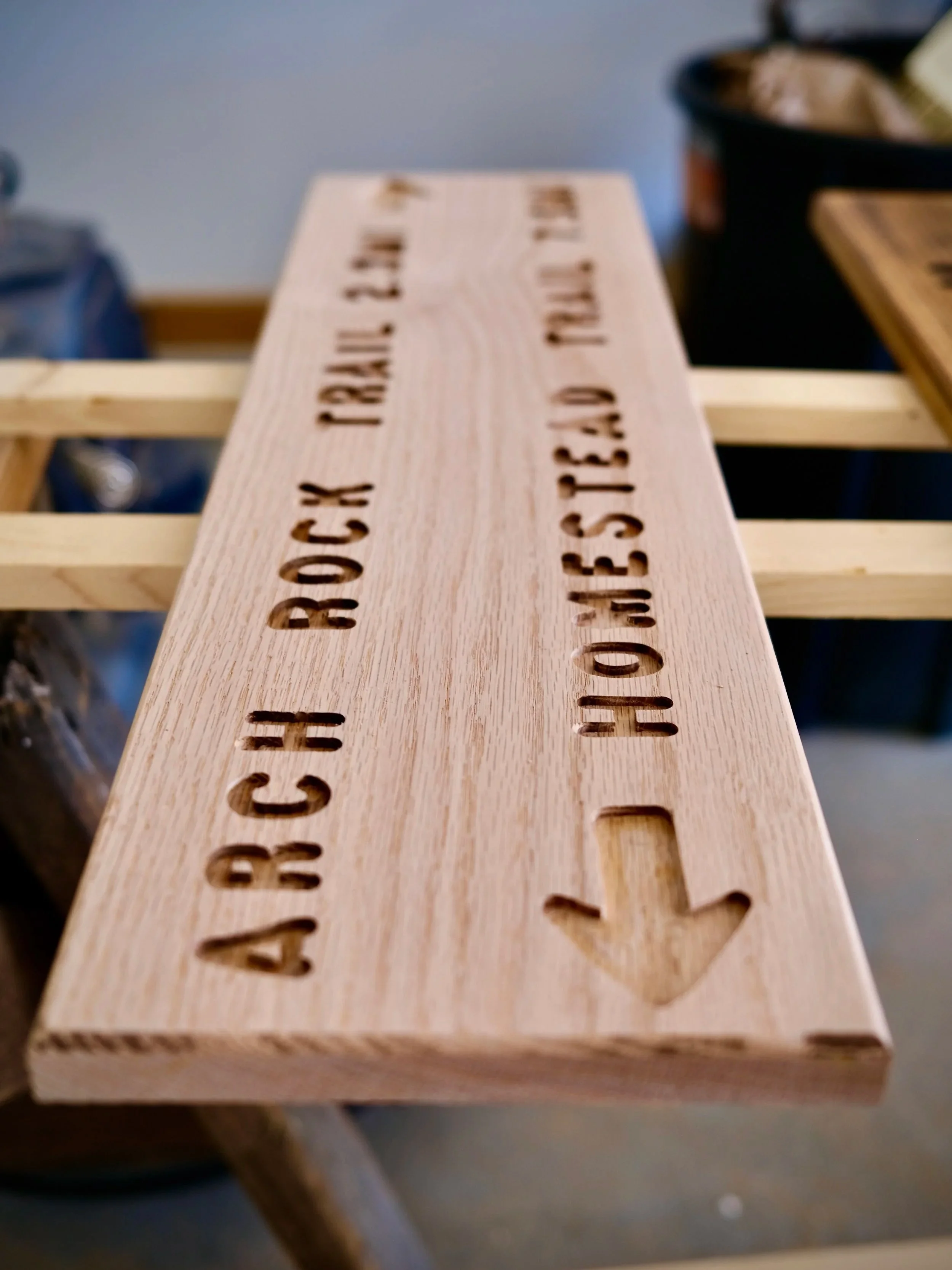 Wooden sign with engraved text and arrow.