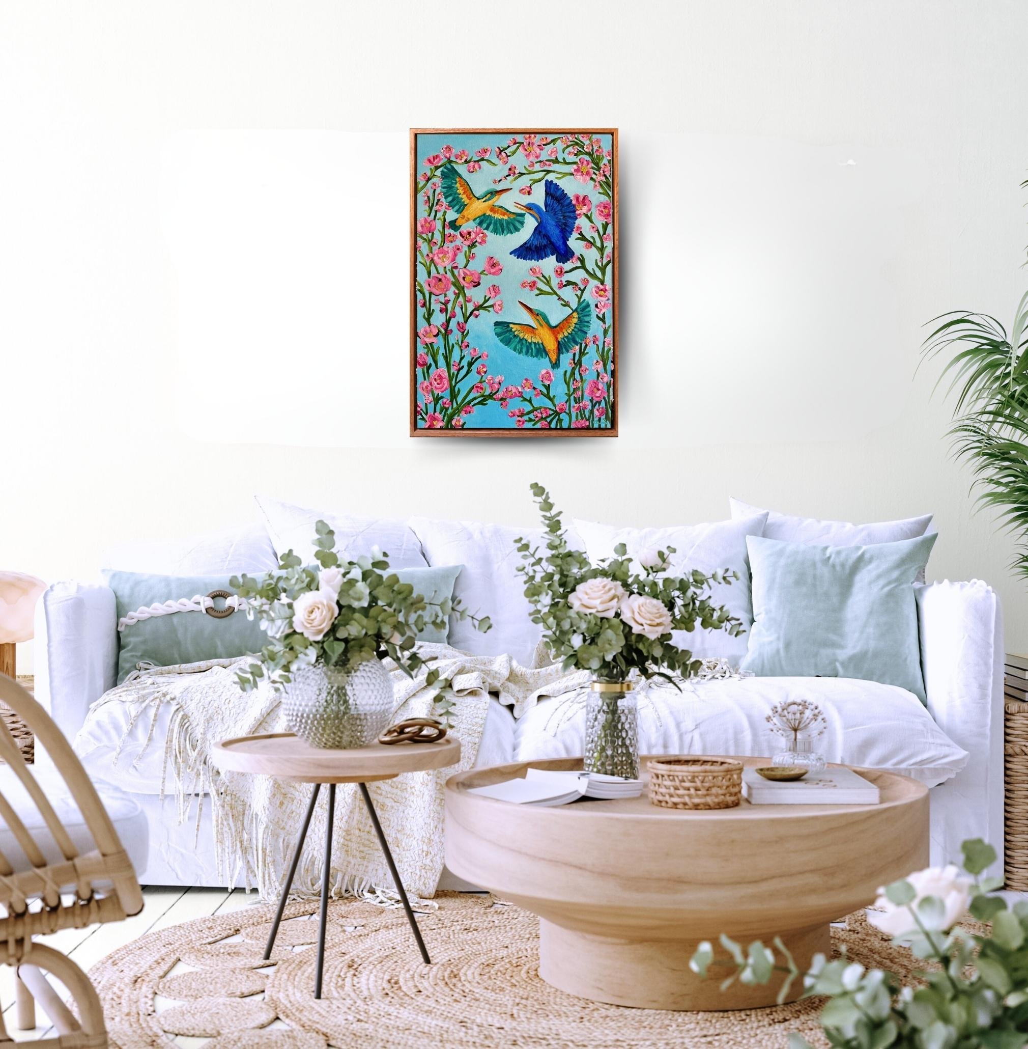 Kingfishers in Flight is an original oil painting by Australian artist Cassie Holmes, and features three beautiful kingfisher birds flying amongst some beautiful soft pink flowers.