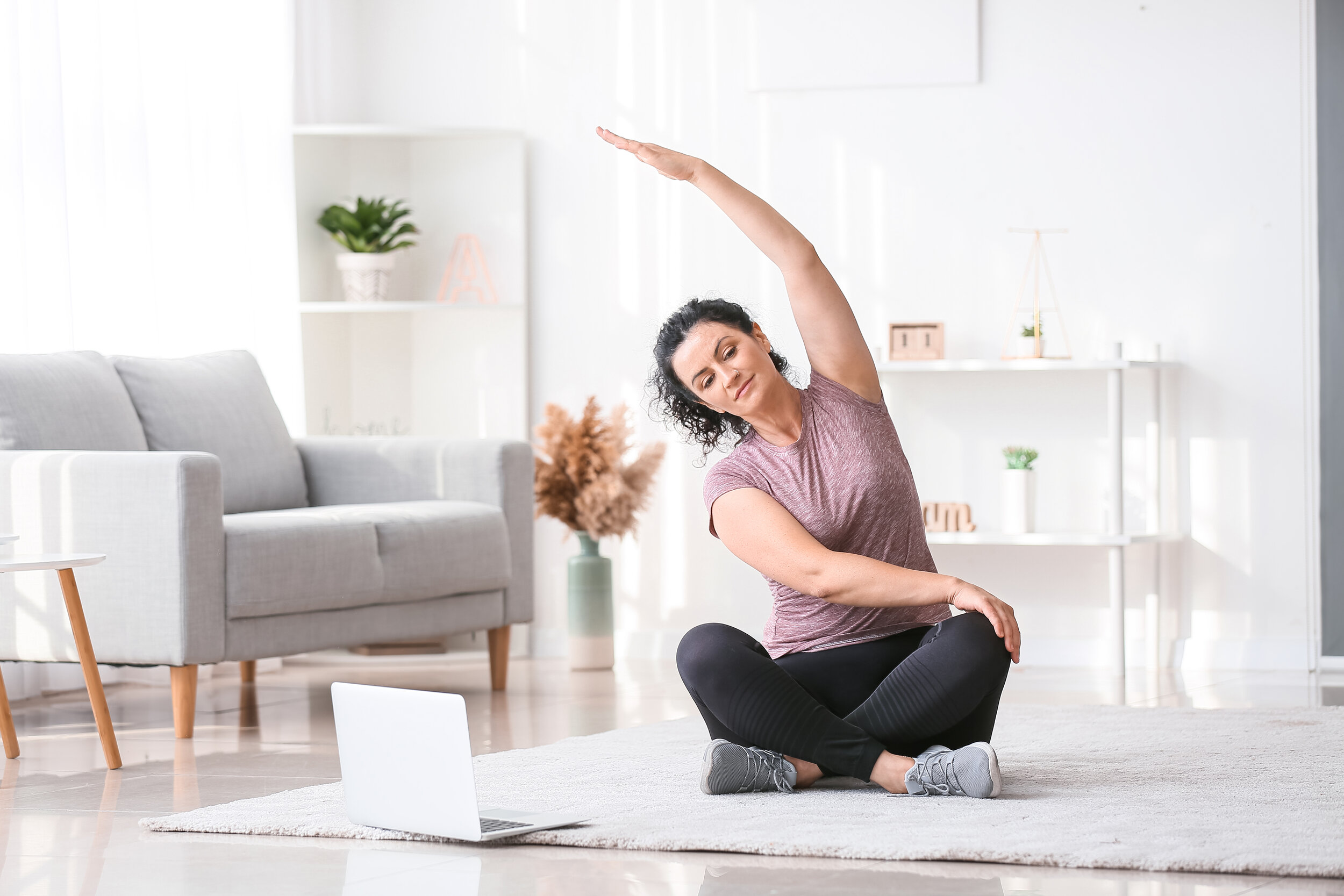 Lady stretching in front of laptop seated.jpg