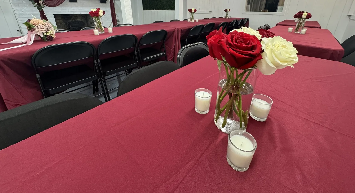 Red and white rose centerpiece on a burgundy table at a bridal shower
