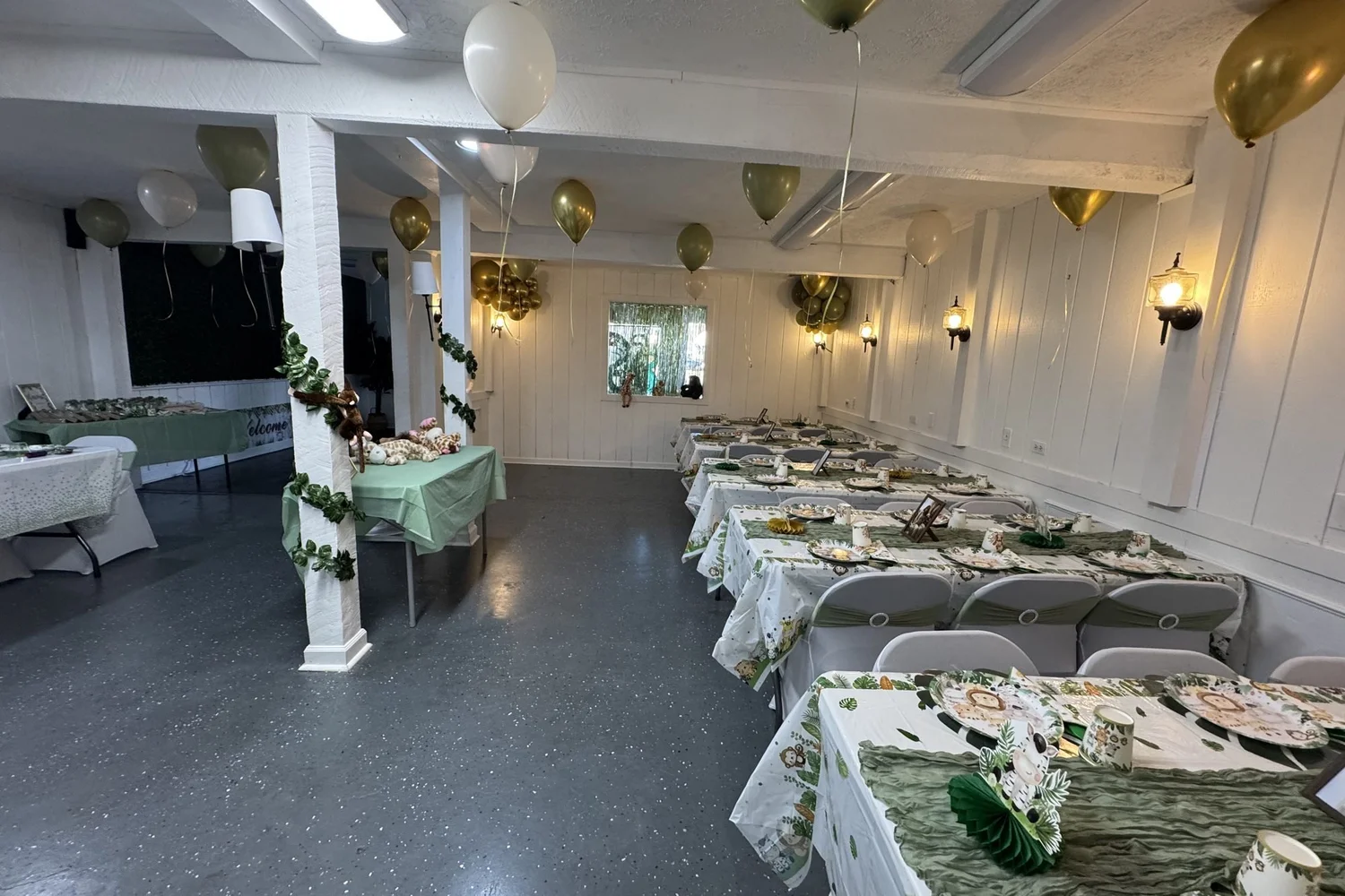 Full main room set with long tables, sage runners and gold balloons, view from the entry
