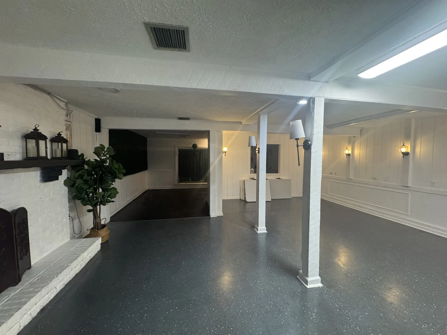 Main room view past the white brick fireplace and columns toward the back of the venue