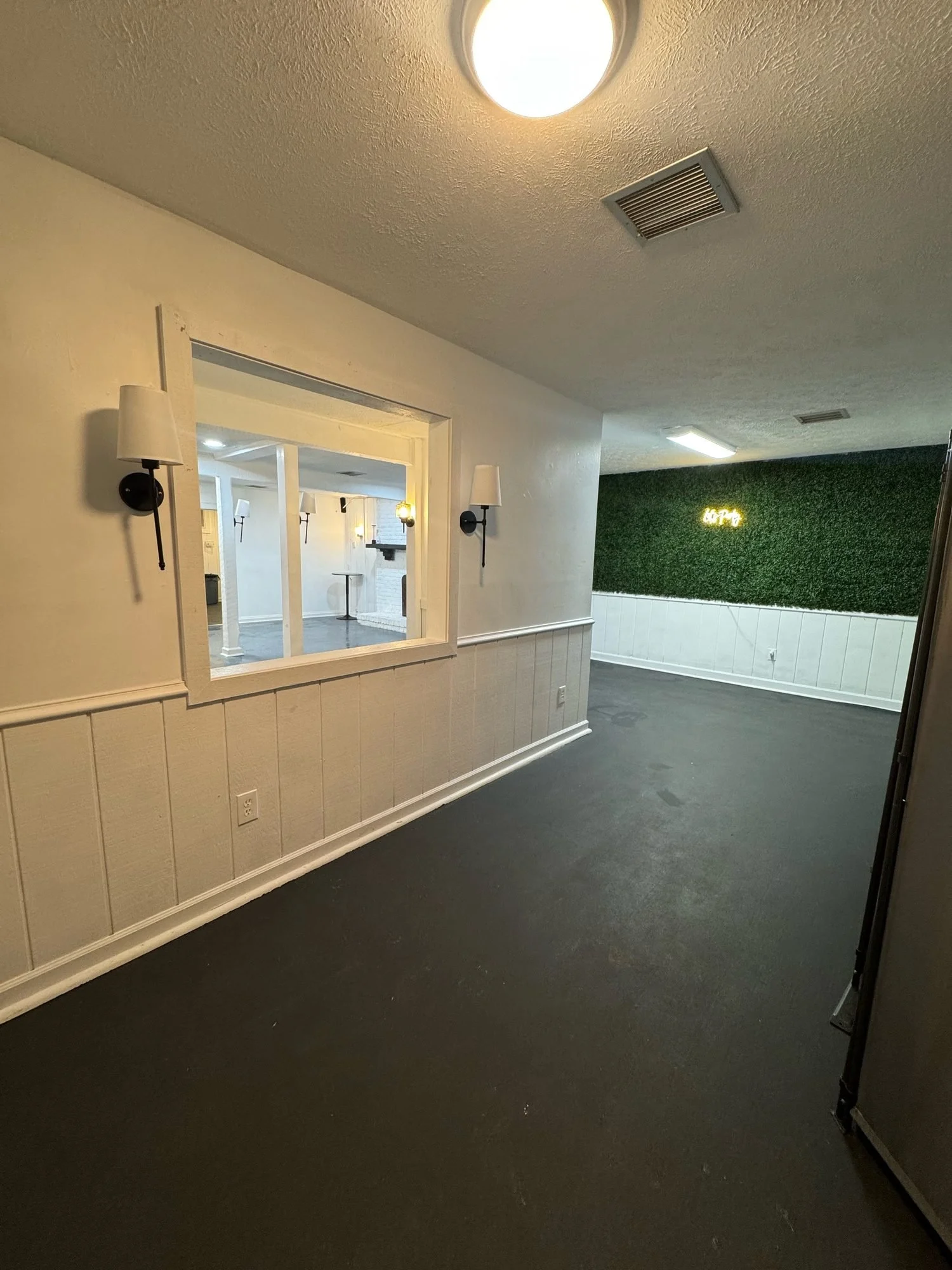Foyer with a pass-through window into the main room and the boxwood greenery wall at the far end