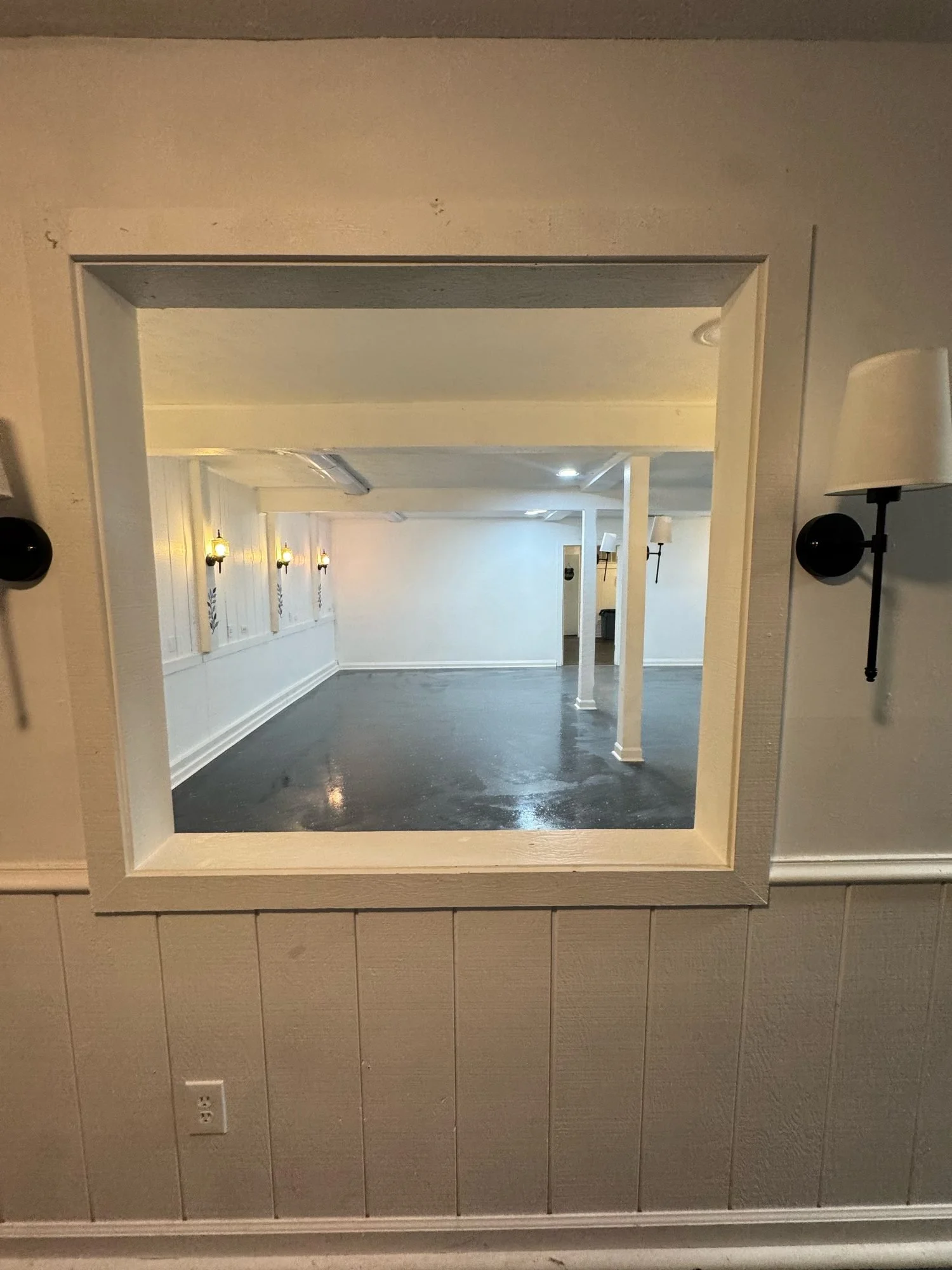 Foyer pass-through window framed by two wall sconces, looking into the main room