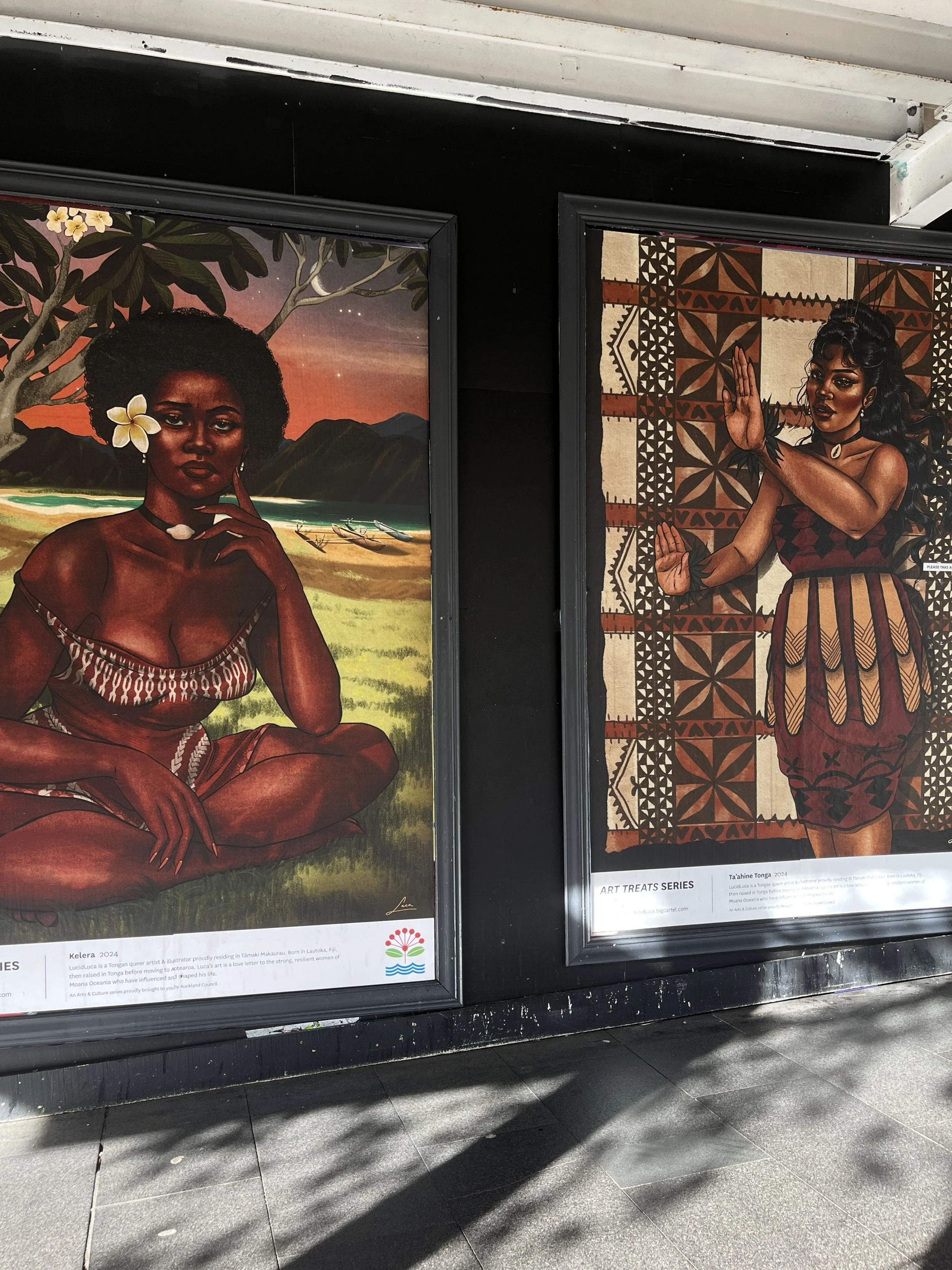 Two mural paintings of women in a cultural art series, one with natural hair and a flower, the other wearing traditional attire, displayed in a public setting.