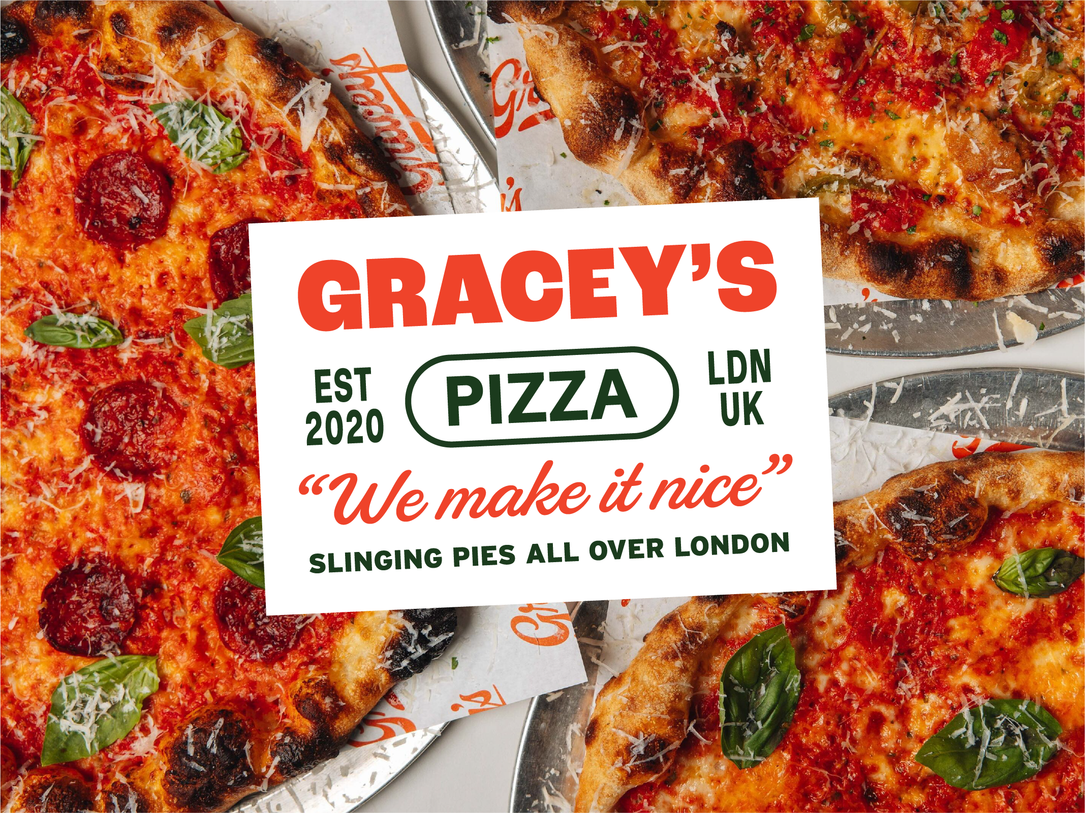 Various slices of pizza with toppings like pepperoni, basil, and grated cheese on a tray at Gracey's Pizza shop.