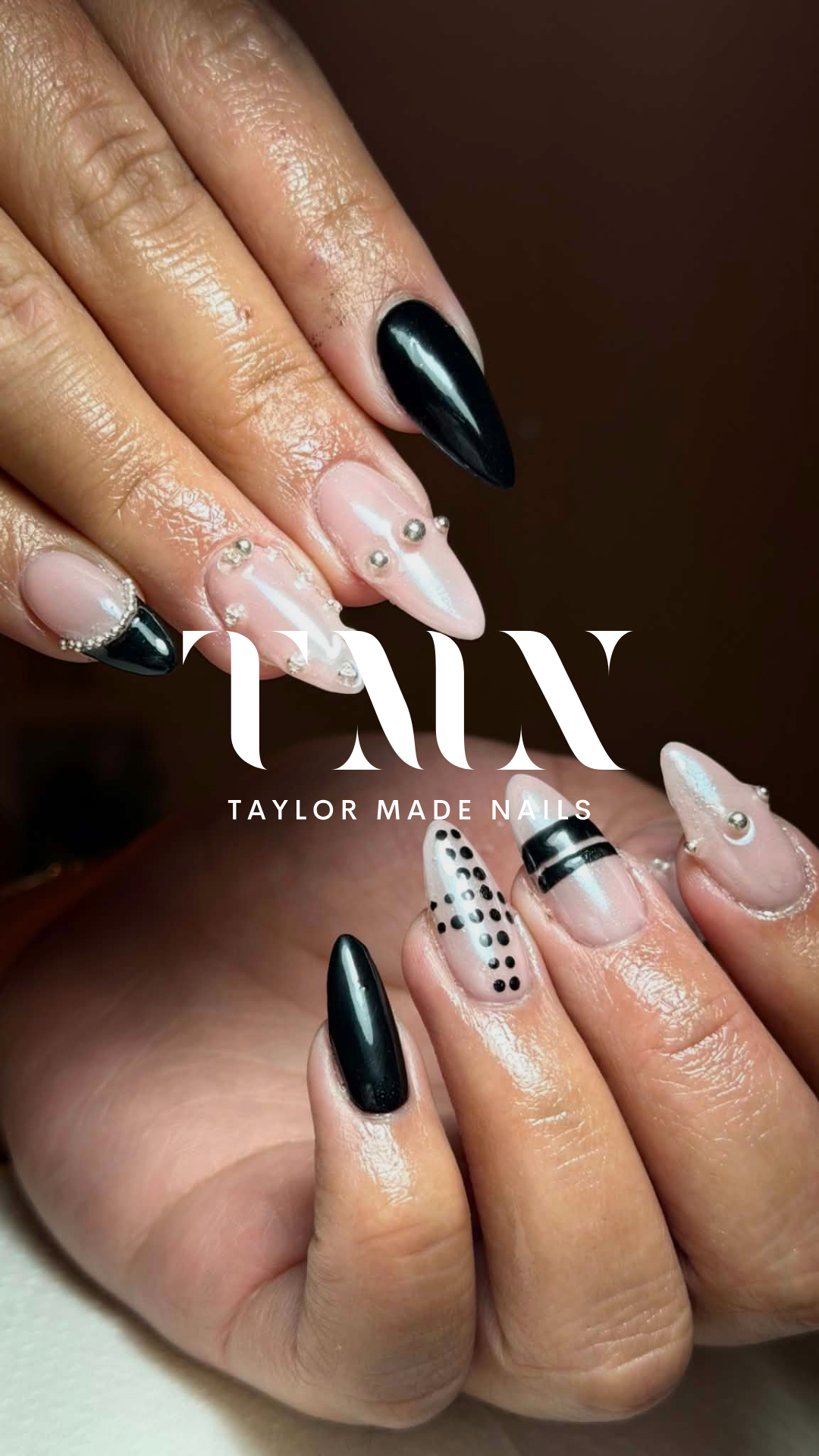 Close-up of a hand with black and white decorated acrylic nails featuring pearls, dots, and patterns, with the text 'TAYLOR MADE NAILS' overlayed.