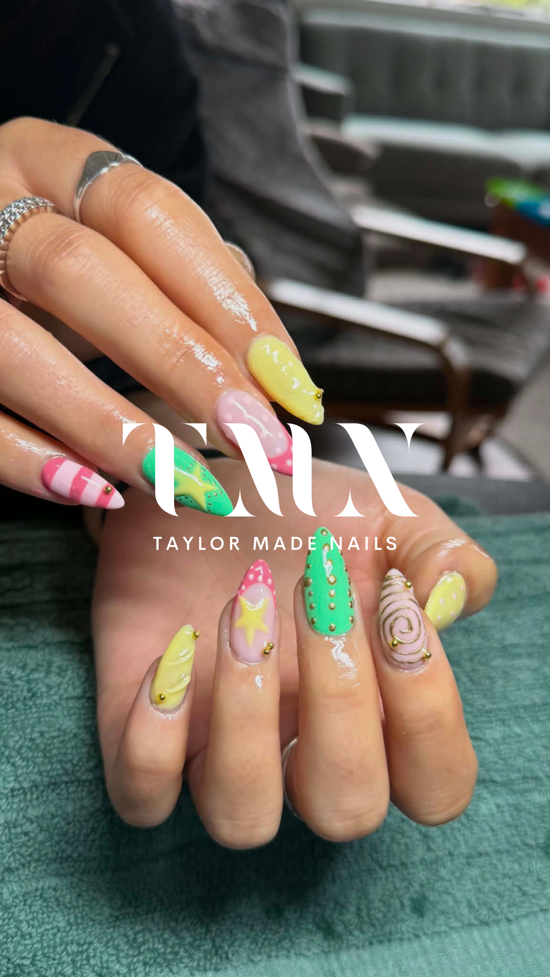 Close-up of hands displaying colorful, decorated nails with summer-themed patterns, beads, and intricate designs, with the text 'TAYLOR MADE NAILS' overlayed.