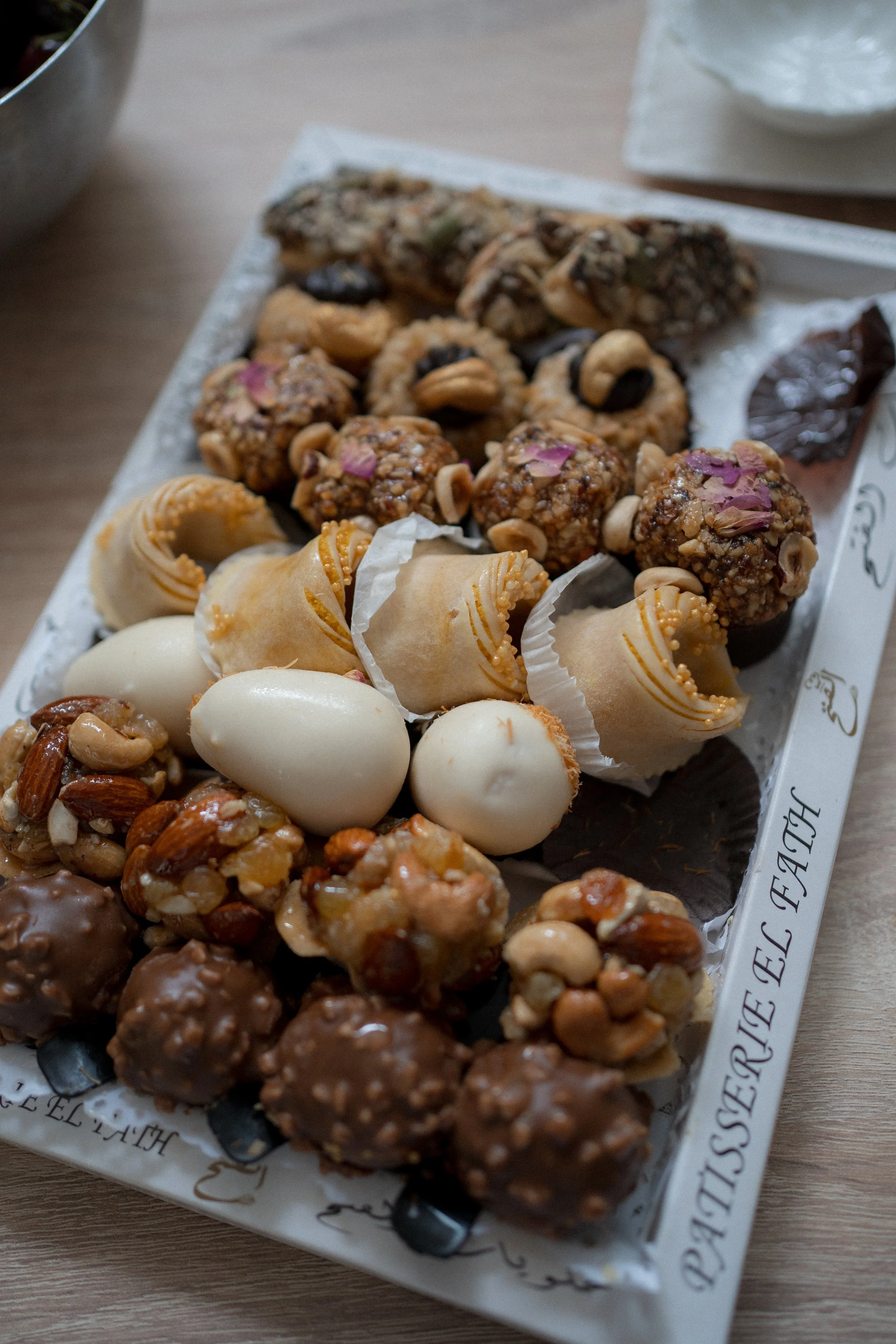Variedad de dulces tradicionales en un bandeja. Incluyen trufas, frutos secos con chocolate, y otros tipos de bocadillos dulces con diferentes formas y colores.