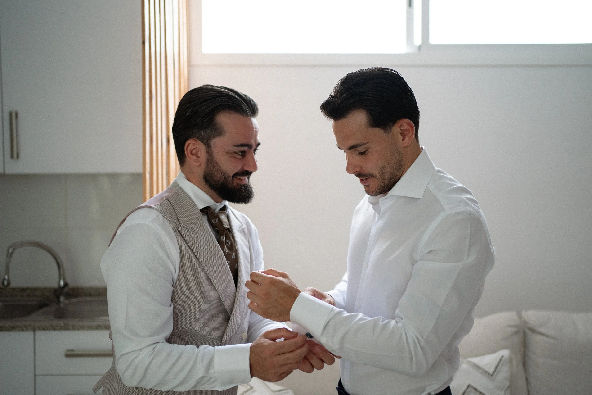 Un hombre ayuda a vestirse a su hermano en los preparativos del novio.