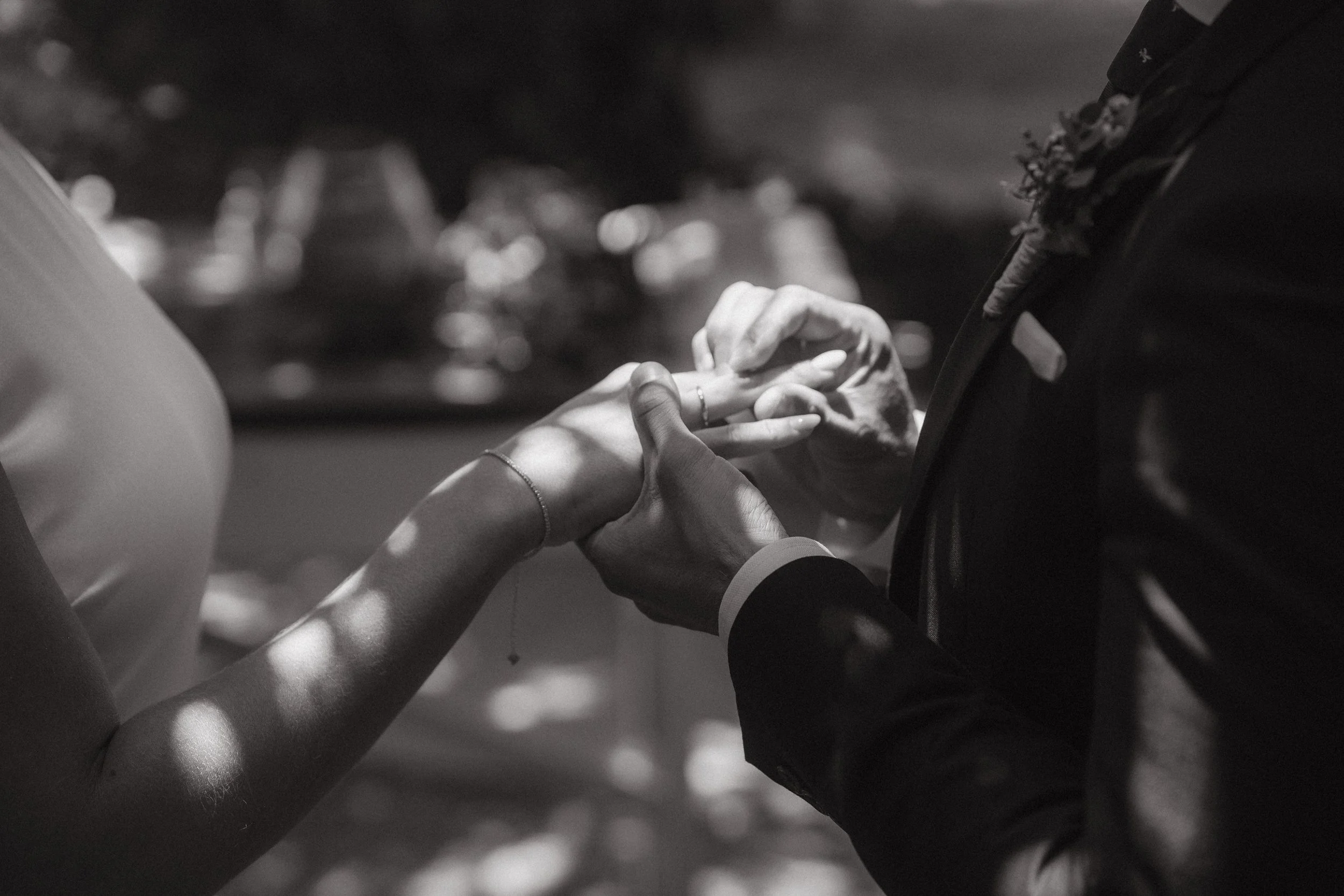 Una pareja intercambiando anillos de boda en una ceremonia, vista en blanco y negro.