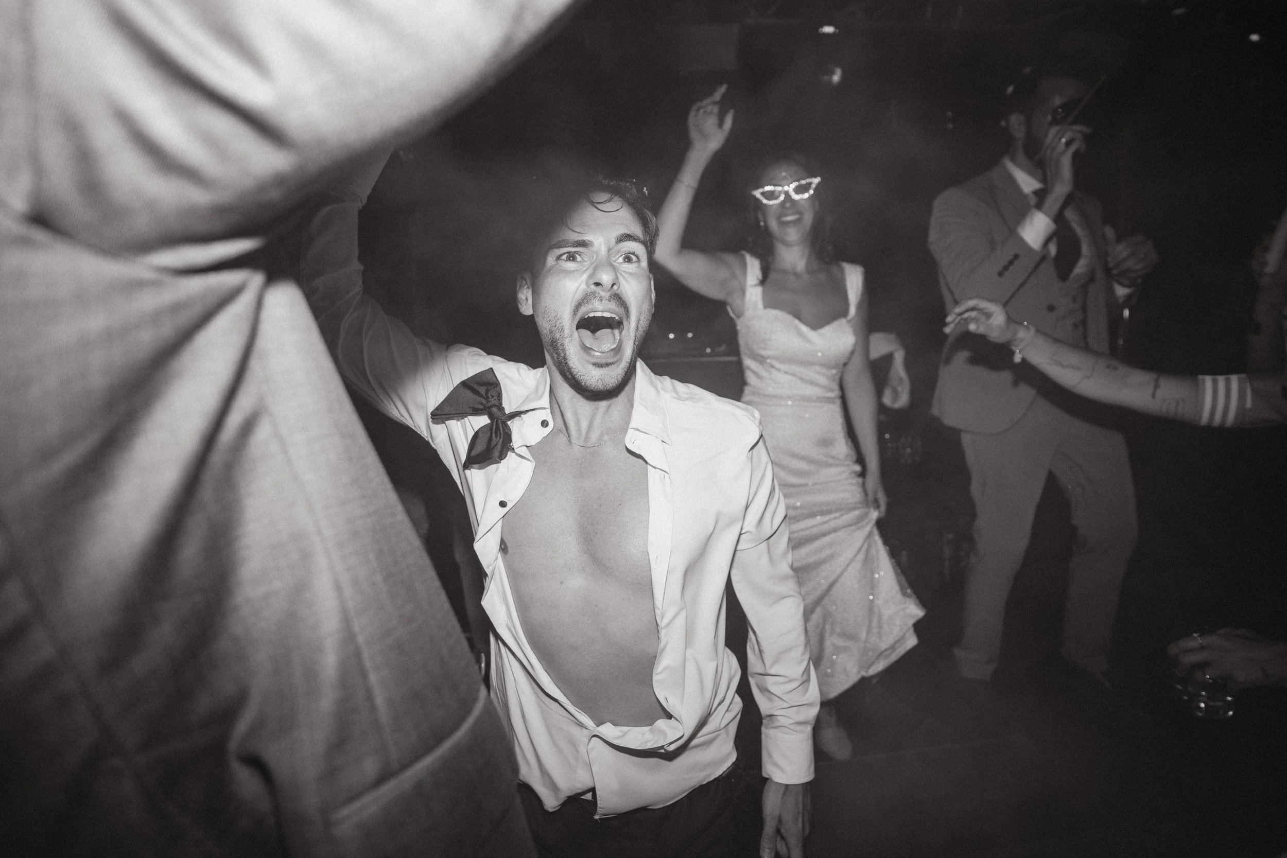 Personas bailando y disfrutando en una fiesta en un ambiente oscuro con poca iluminación.