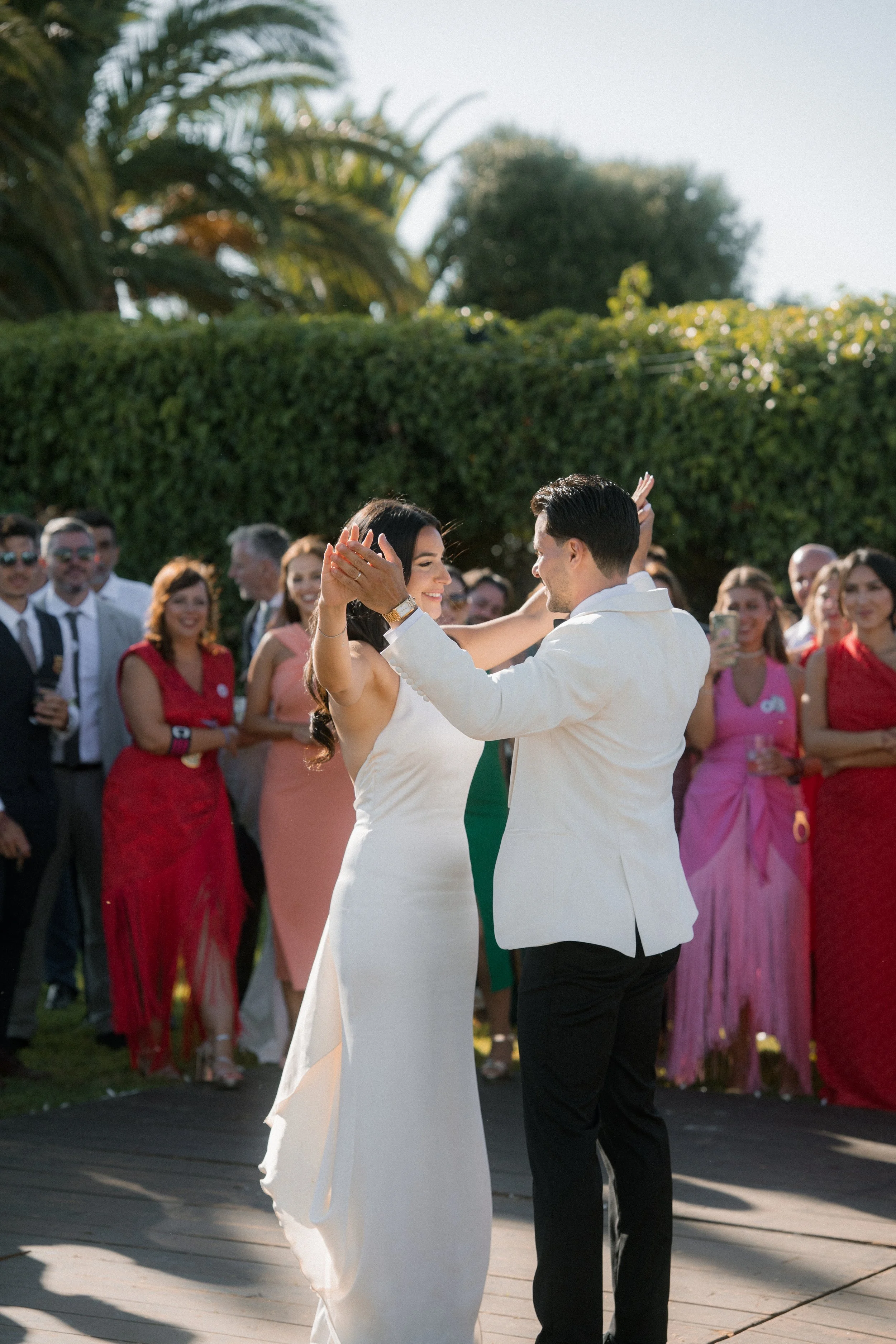 Pareja bailando en una boda al aire libre con invitados a su alrededor.