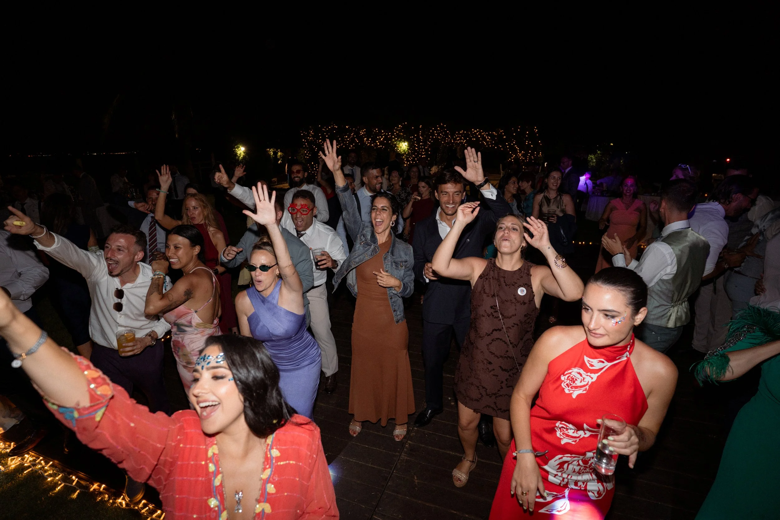 Personas bailando y disfrutando en una fiesta nocturna al aire libre.