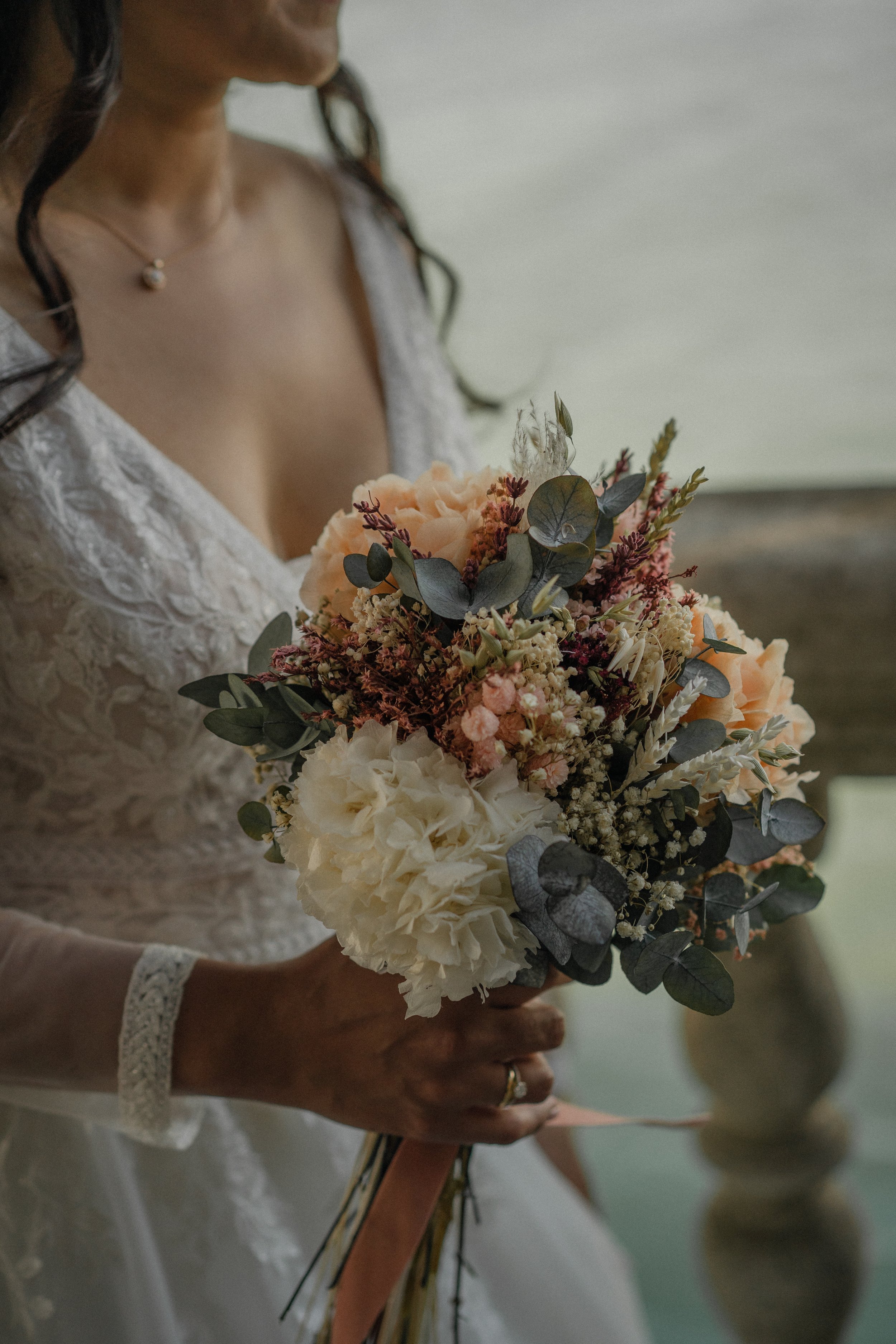 Mujer en un vestido de novia sosteniendo un ramo de flores variadas.