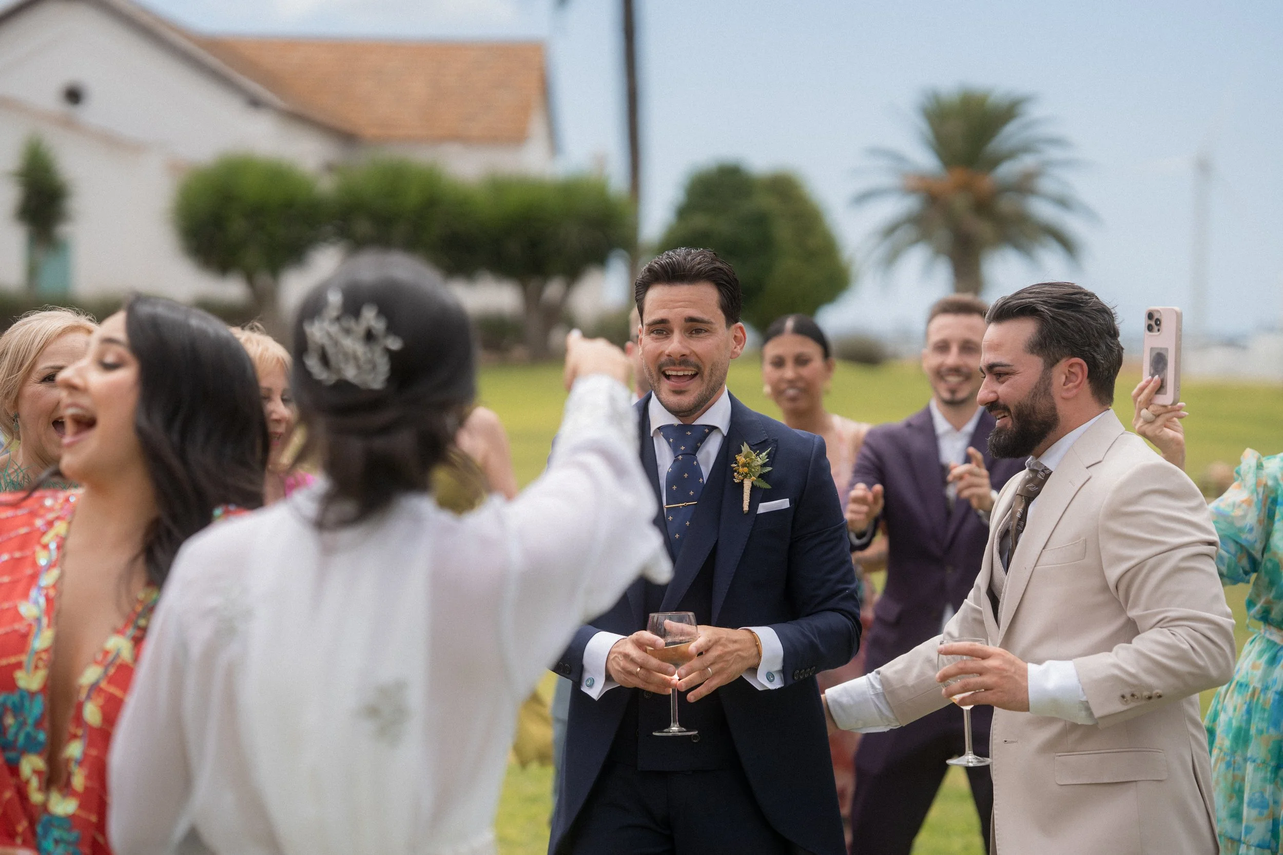 Grupo de personas en una celebración al aire libre, vestido formal, brindando y sonriendo.