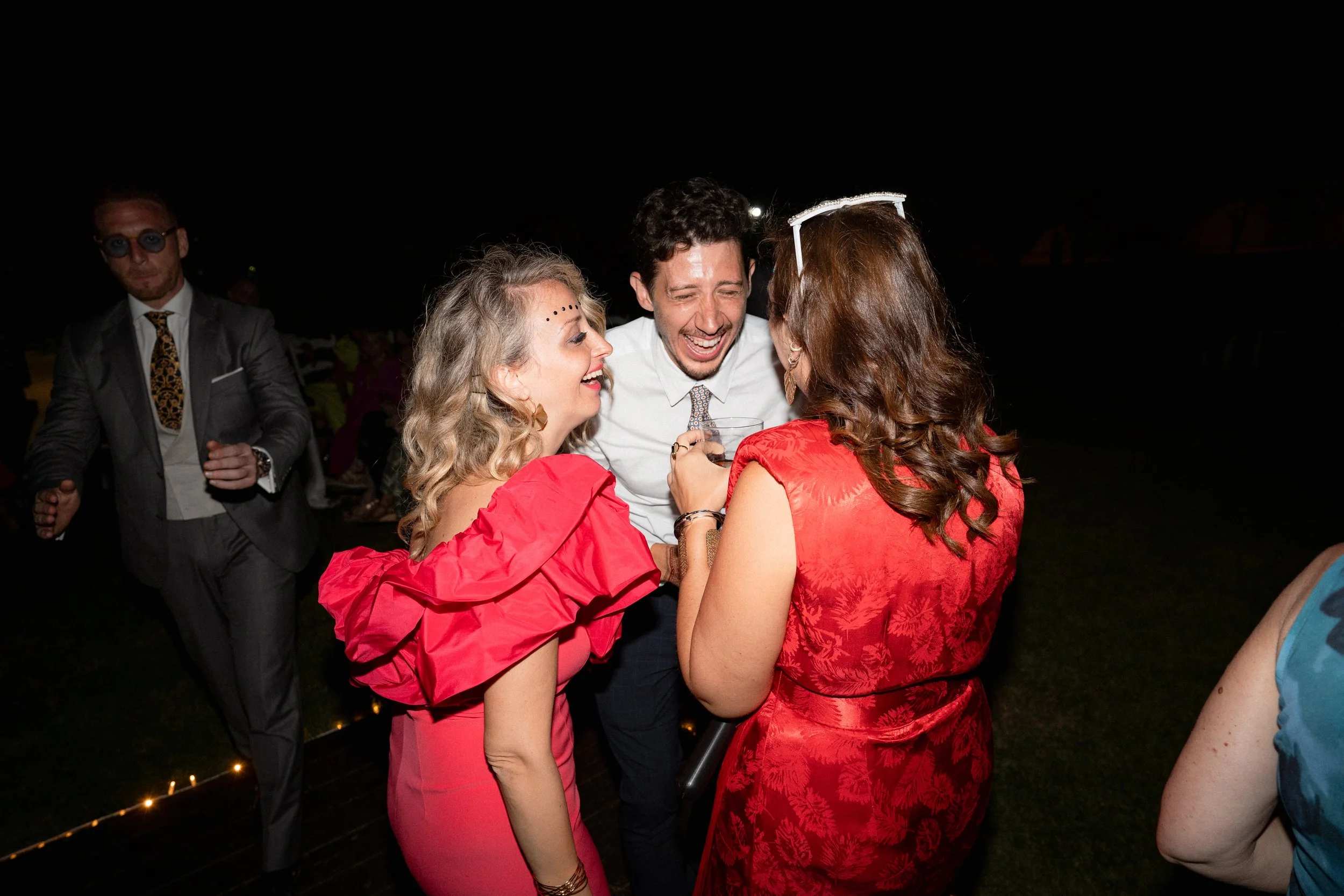 Grupo de personas riendo y disfrutando en una fiesta nocturna, vestido elegante, ambiente alegre.