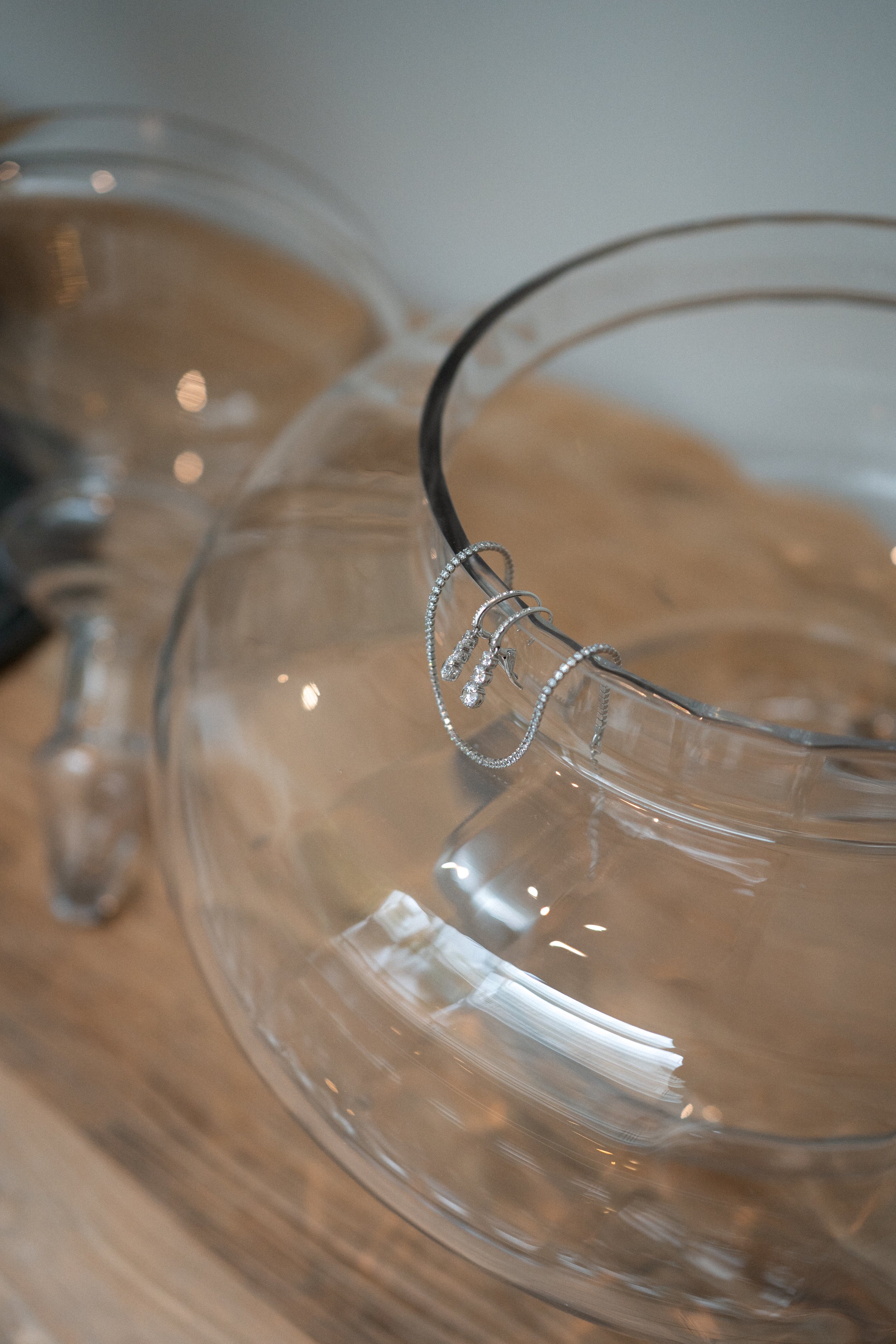Preparativos de la novia, joyería con pulseras y collares de plata colocados en un frasco de vidrio transparente sobre una superficie de madera.