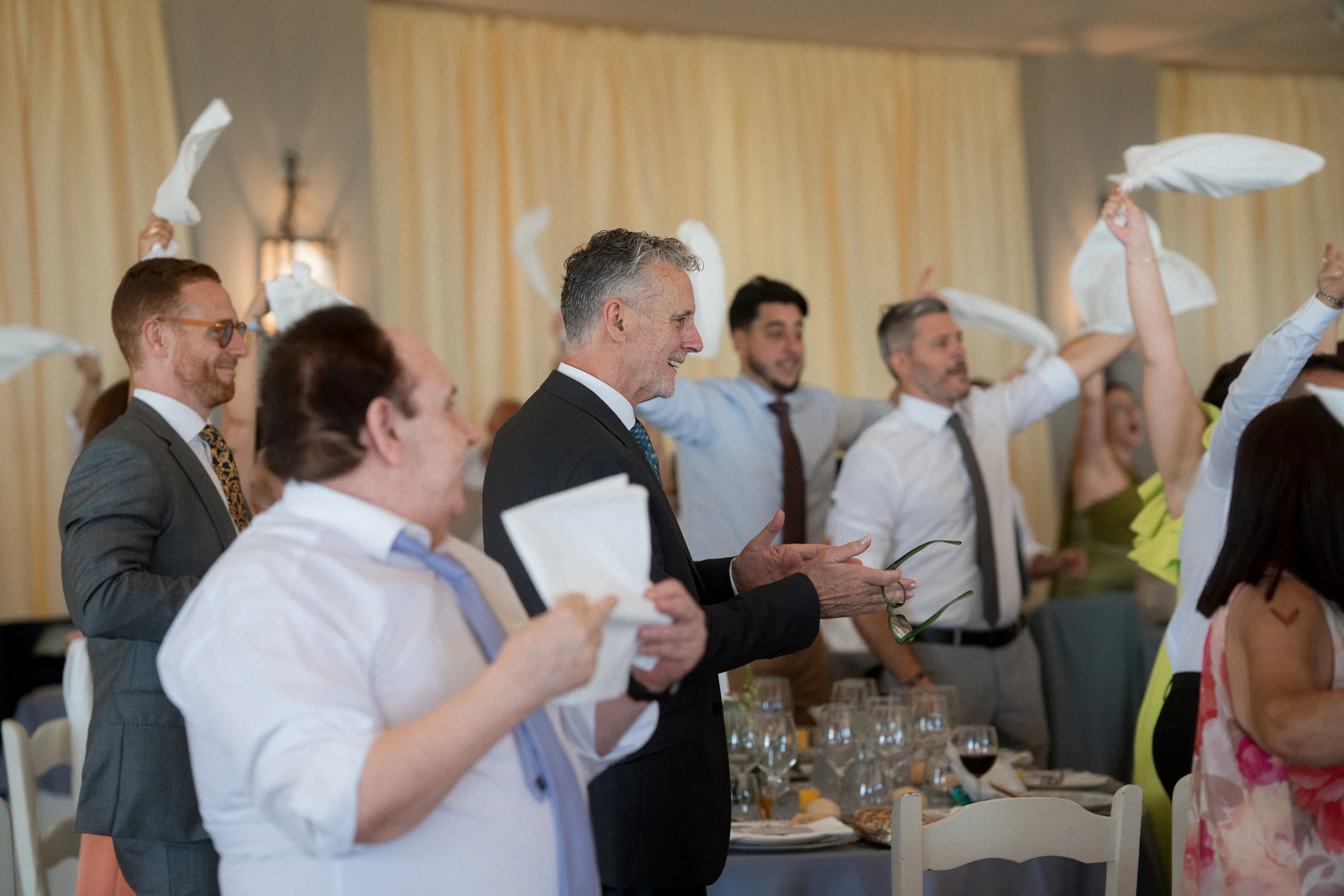 Grupo de personas en celebración, algunas con pañuelos en las manos, en un evento social o reunión en interiores.