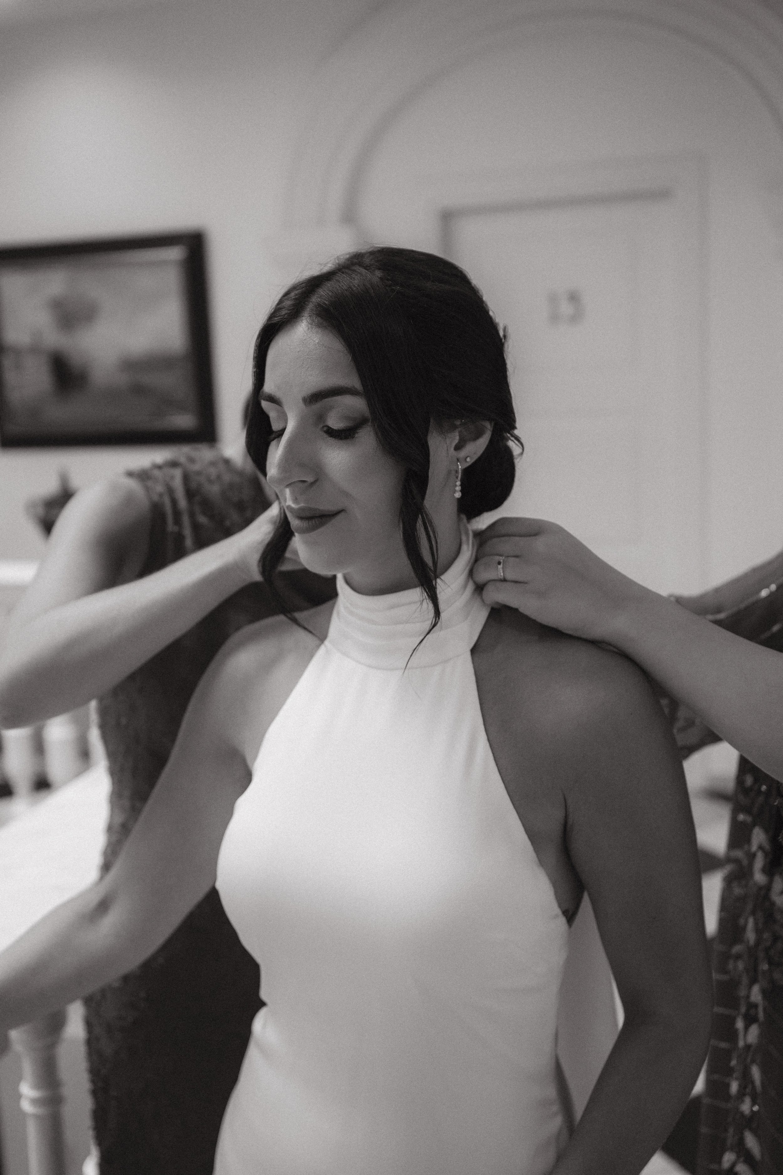 Mujer con vestido blanco, arreglándose antes de un evento, en un ambiente interior.
