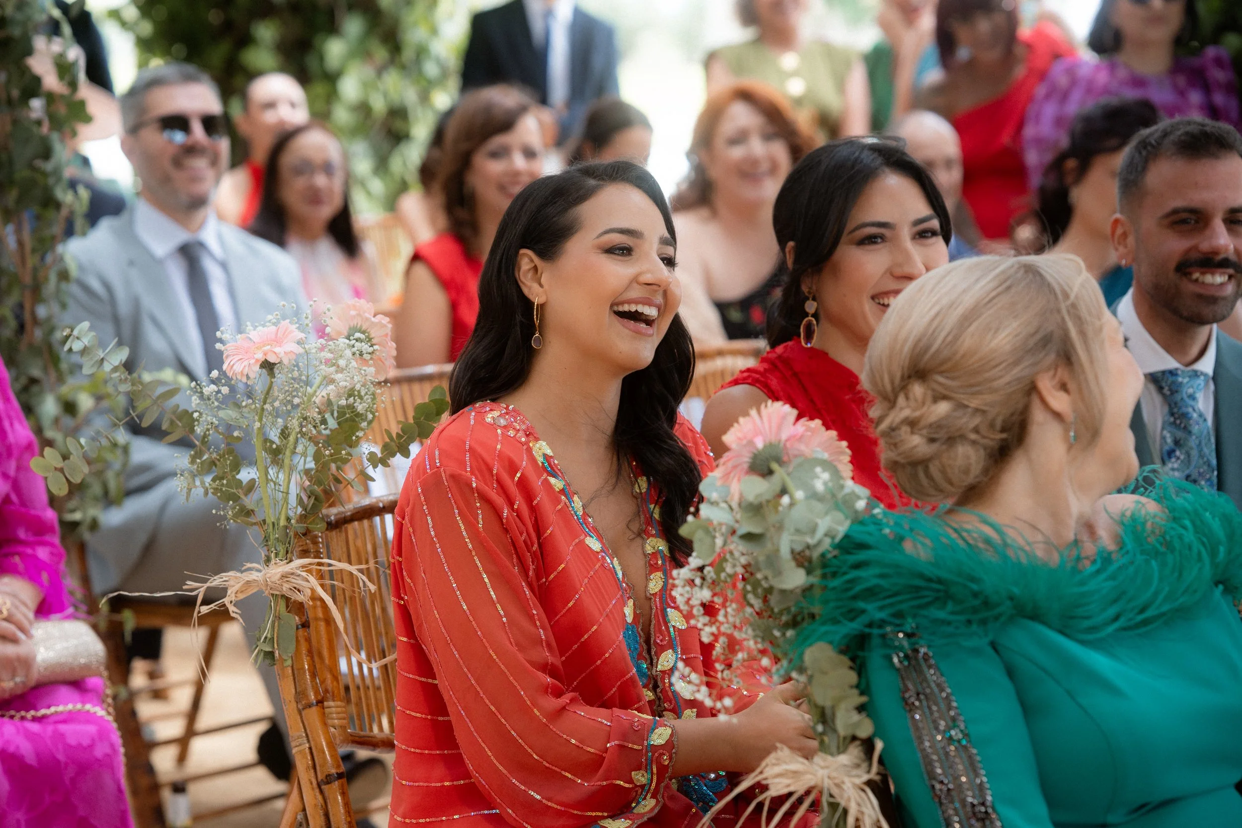 Reunión de personas en un evento al aire libre, la mayoría son mujeres vestidas con ropa colorida y elegante, riendo y disfrutando del momento, con algunos hombres en el fondo.