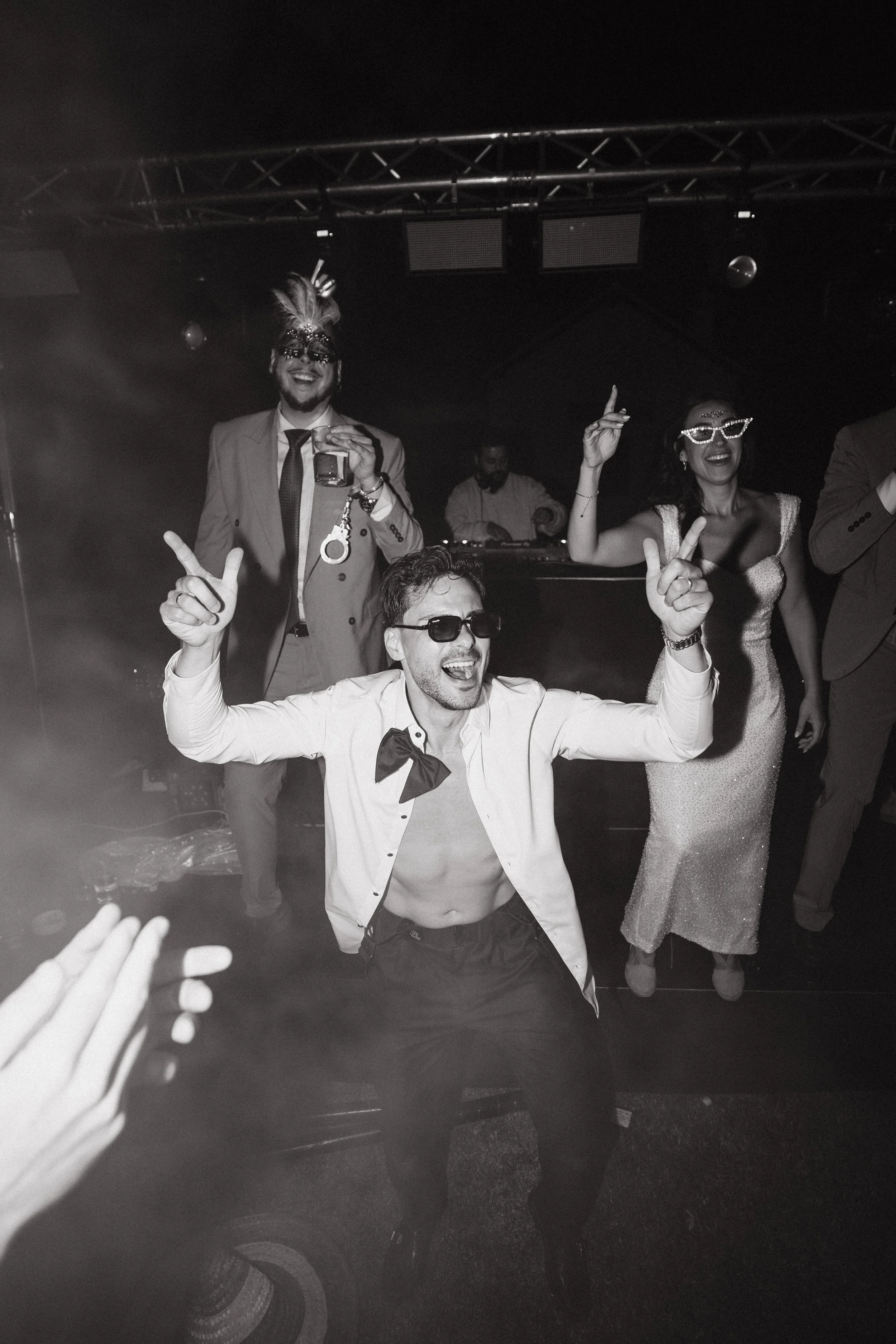 Grupo de personas bailando y disfrutando en una fiesta, algunos con disfraces y accesorios divertidos, en un ambiente de noche, con música y luces.