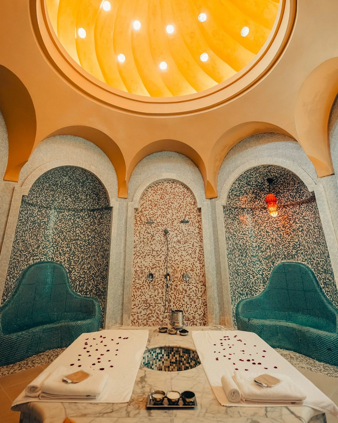 A tall, historic tower with intricate architectural details, surrounded by palm trees under a partly cloudy sky.