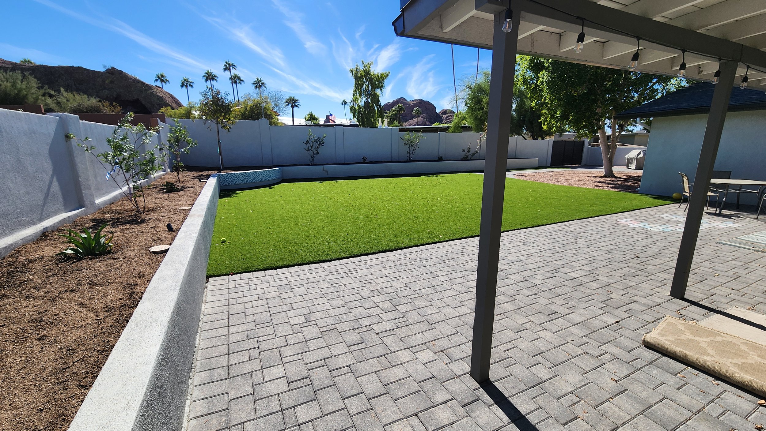 Backyard remodel in Scottsdale, AZ with new raised planter, soil, planting, pavers, artificial turf, low voltage lighting, and sch 40 PVC drip irrigation