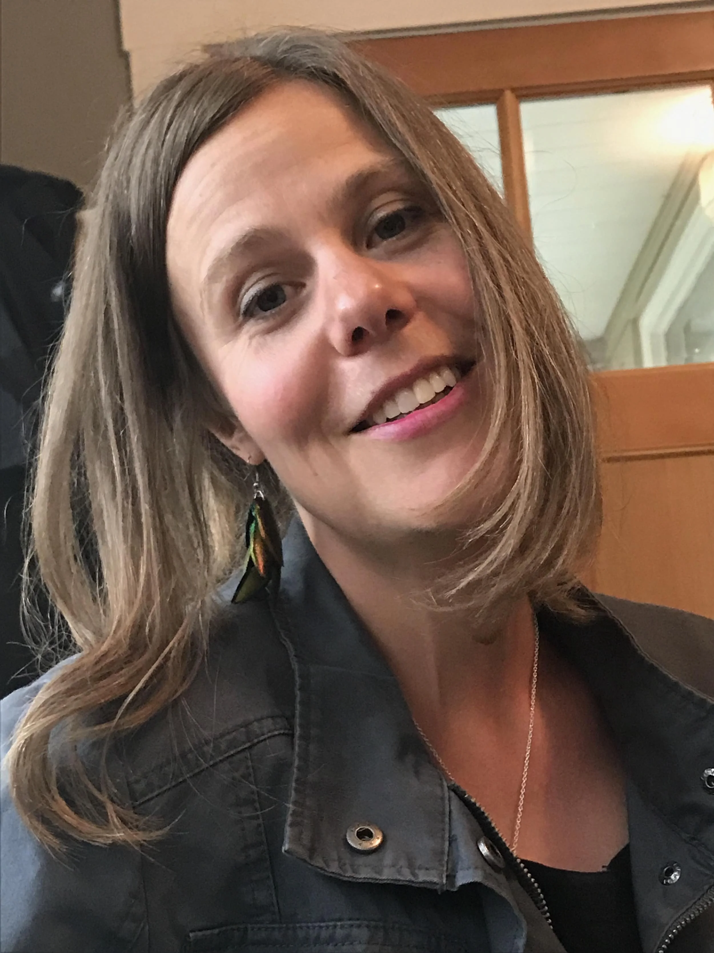 Ria de Neeve, astrologer, with long sandy blonde hair, without glasses, smiling