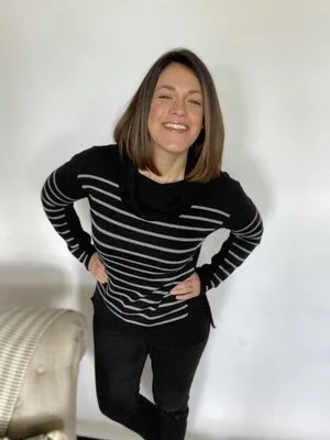 A smiling woman's indoor selfie, illustrating photography ideas and tips for a good selfie with a propped-up phone.