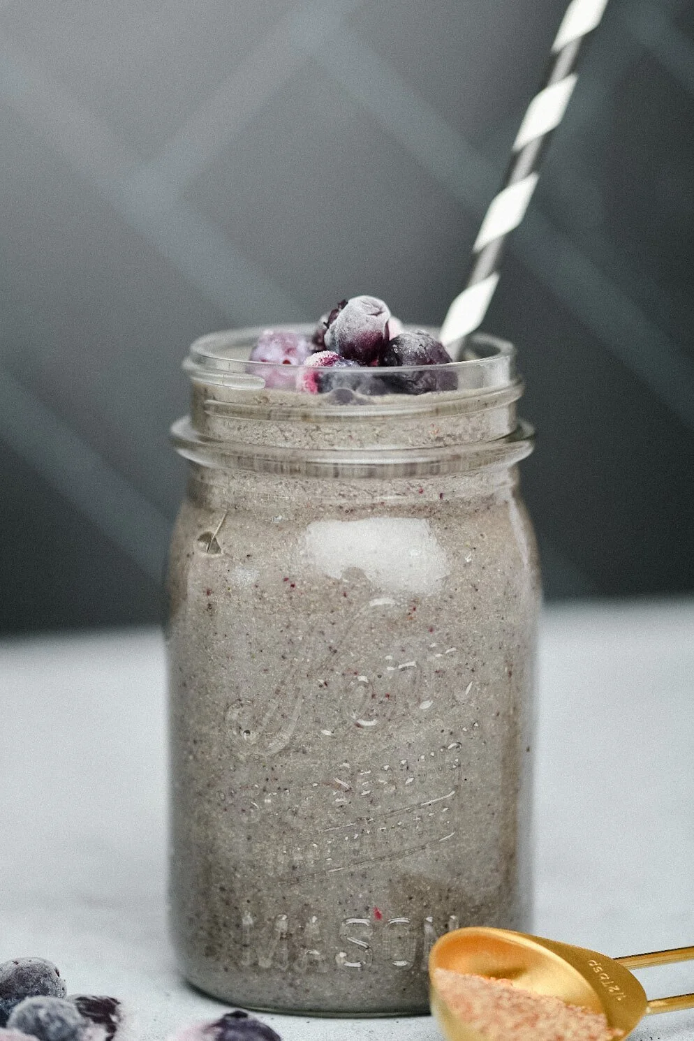 A superfood smoothie in a mason jar with a striped straw, from a blog post about a superfood smoothie recipe.
