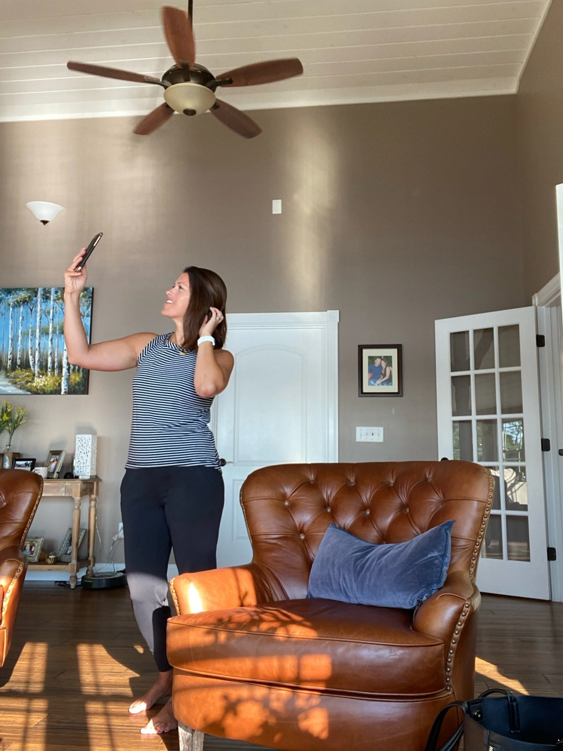 A woman holding her phone at a high angle to take a selfie, illustrating tips on taking a good selfie.