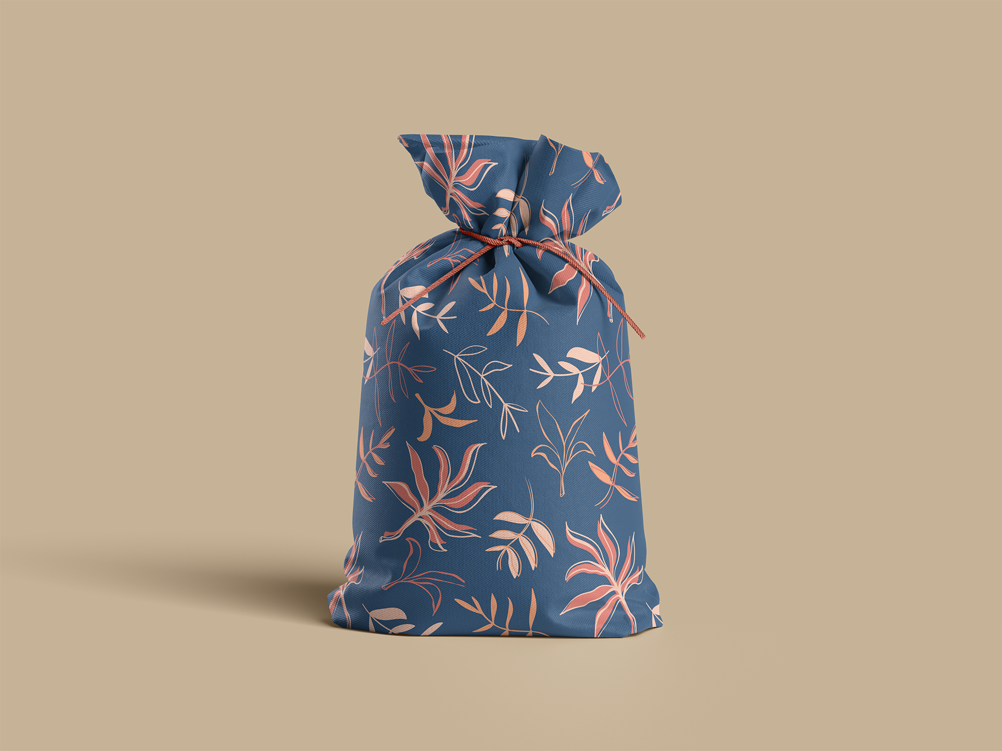 A fabric gift bag with a blue background and a pink leaf pattern, tied with a pink string, against a beige background.