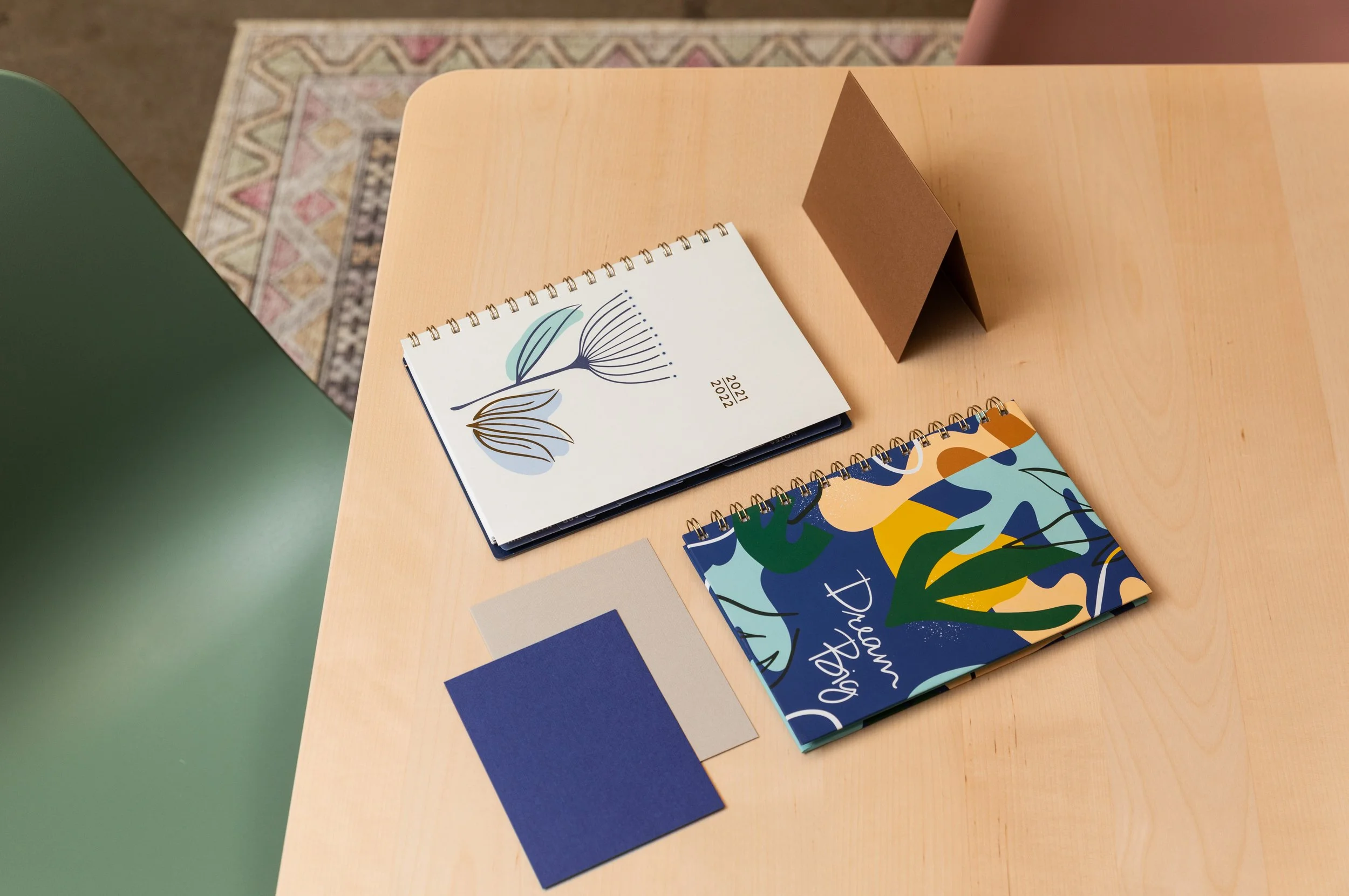 Several 2022 planners and notebooks with colorful covers and designs on a light wood table.