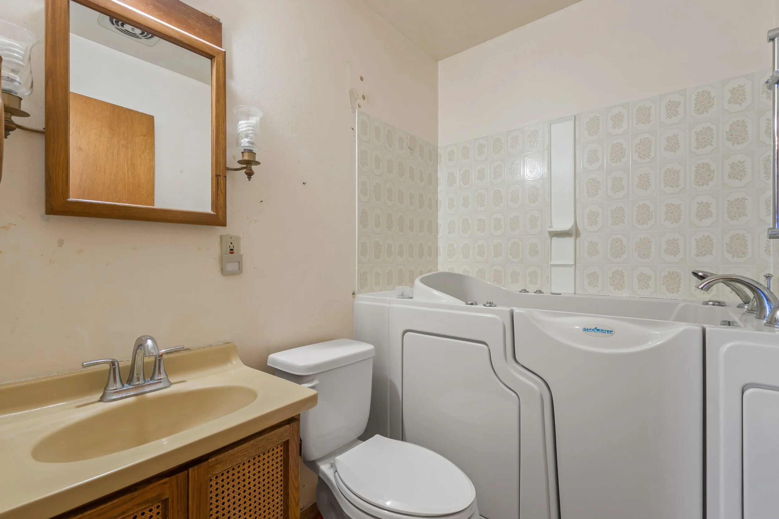 Full bathroom with step-in therapeutic tub, tiled surround, vanity with integrated sink, and wall-mounted lighting. Designed for accessibility and functionality, this bathroom adds versatility and value to this Santa Cruz County property.