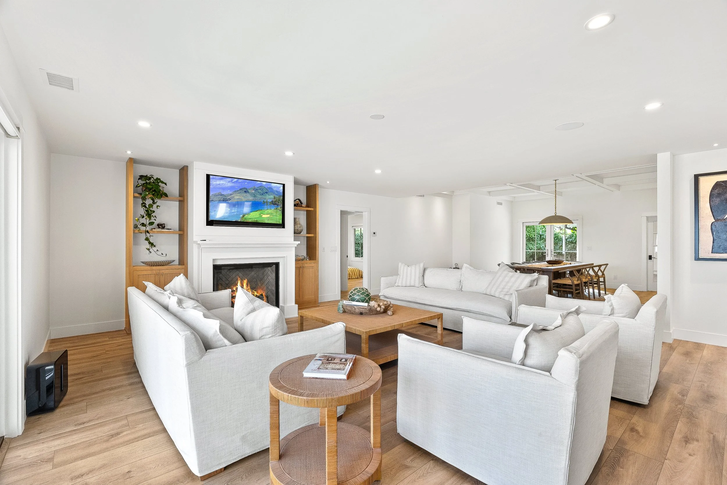 Bright living room with white sofas, a fireplace, a wall-mounted television, wooden accents, and hardwood floors Capitola, California.