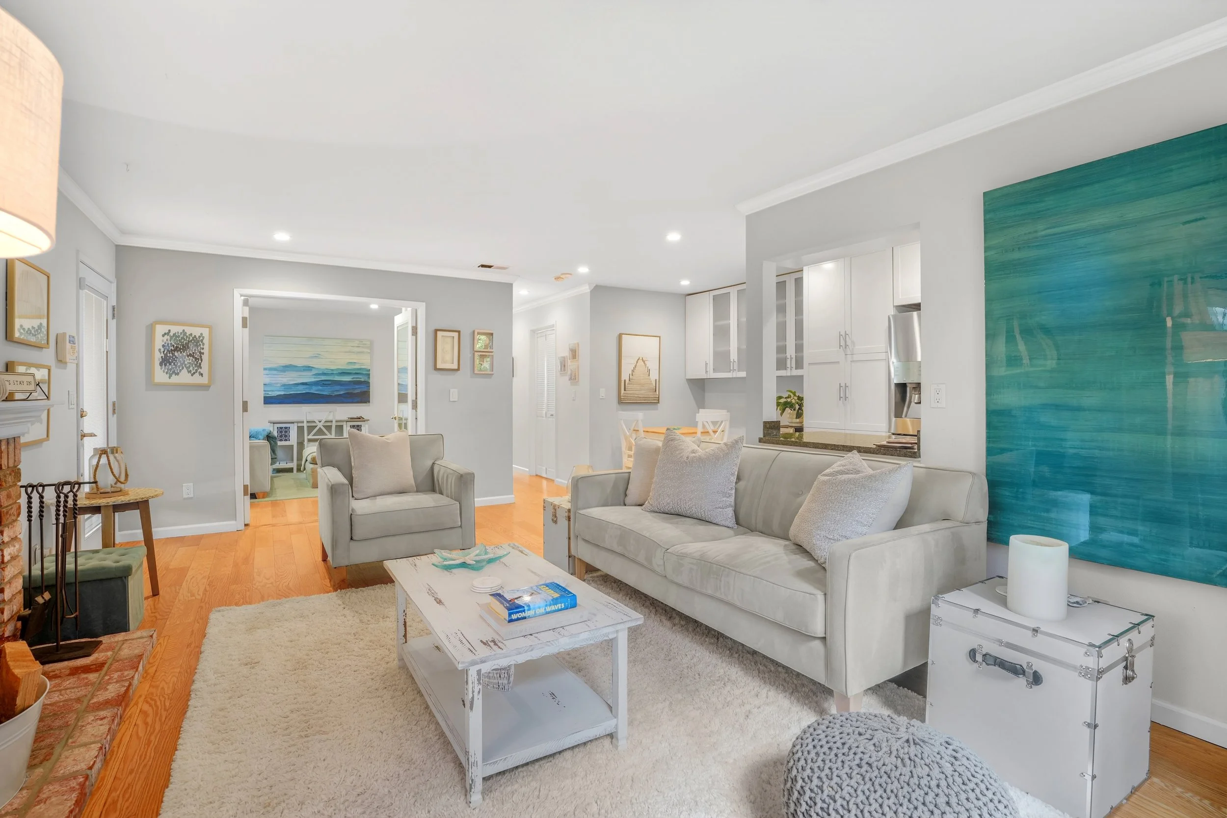 Bright, welcoming living room with light-colored sofa, armchair, coffee table, and wall art, featuring a blue accent wall and hardwood flooring in 1400 Dolphin Dr., Aptos CA..