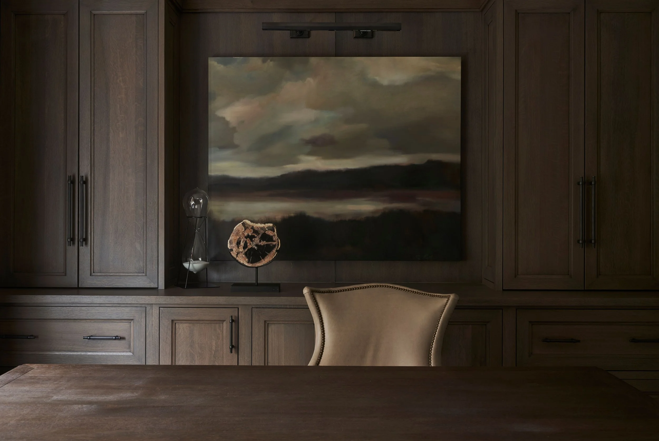 Dark, calming home office design with layered lighting and sleek cabinetry.