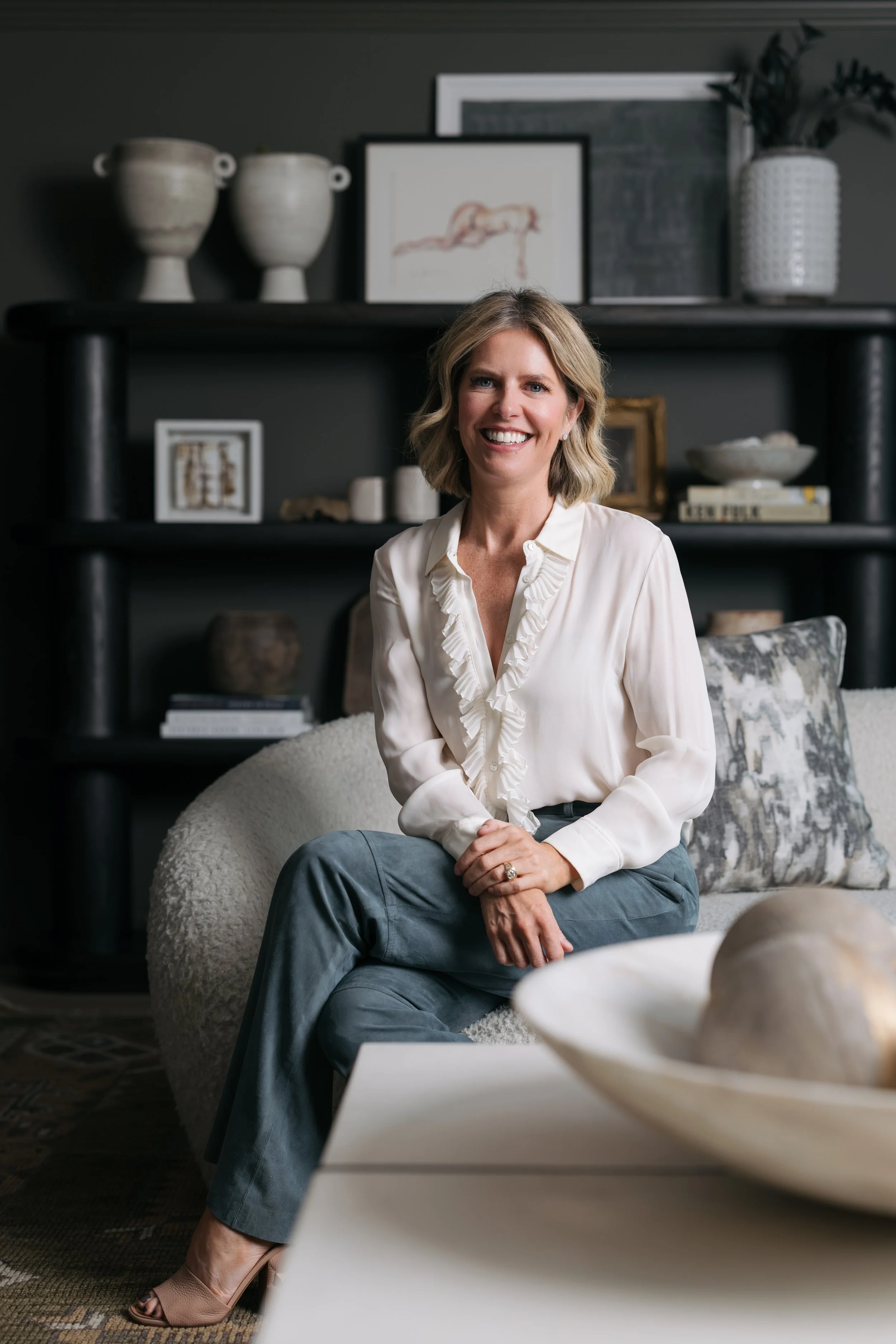 Elizabeth Krueger, Principal and Founder of Elizabeth Krueger Design, seated in a styled room with dark shelving
