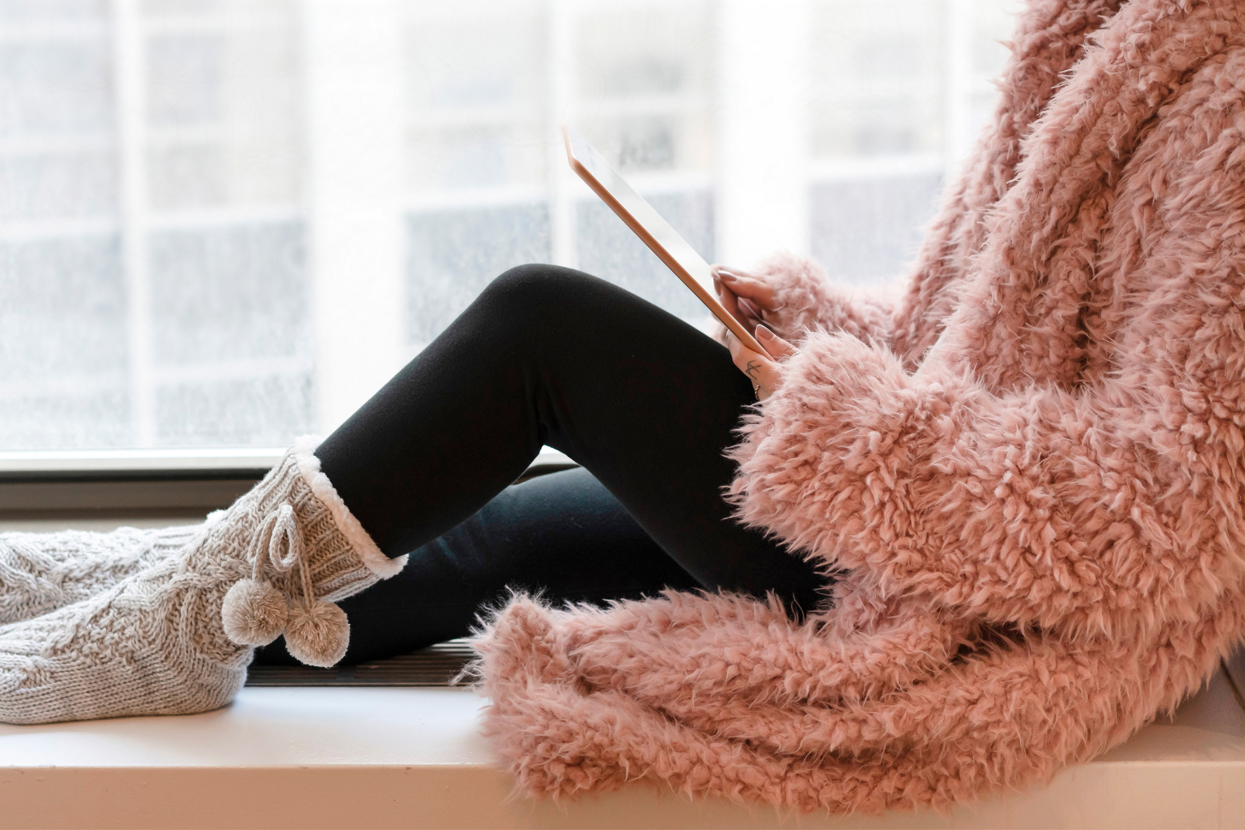 Image of a woman in a window seat looking at a tablet - Kajabi Course Design
