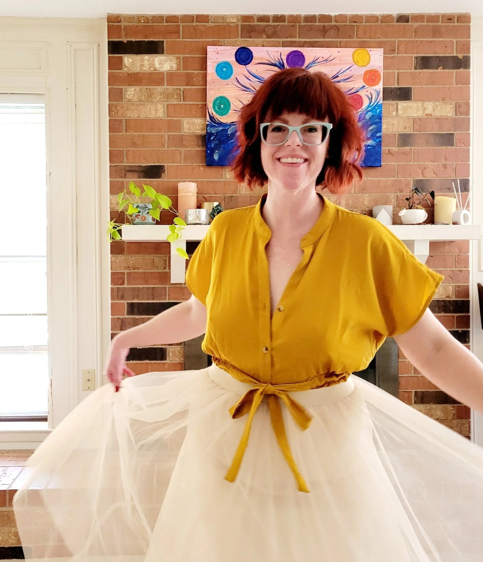 Kate Smith, Website Designer for small businesses is pictured wearing glasses and a yellow top, smiling and looking at the camera.
