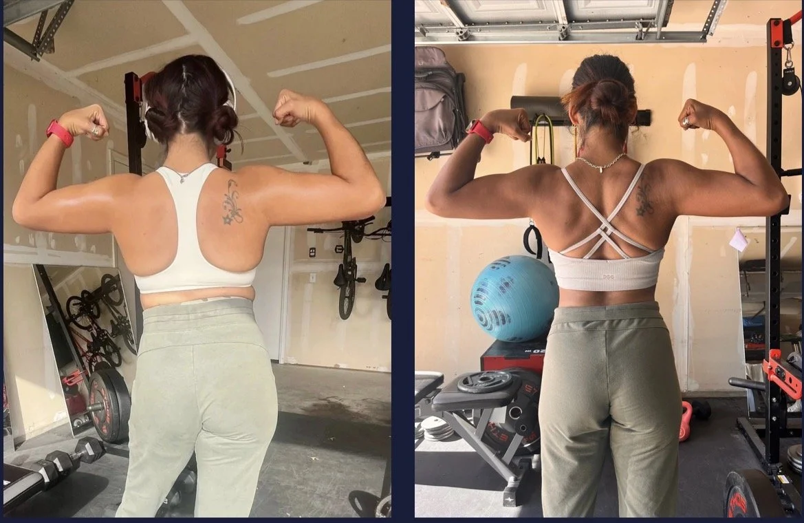 A woman showing her back muscles while flexing her arms in a garage gym, wearing a sports bra and sweatpants, with workout equipment visible in the background.