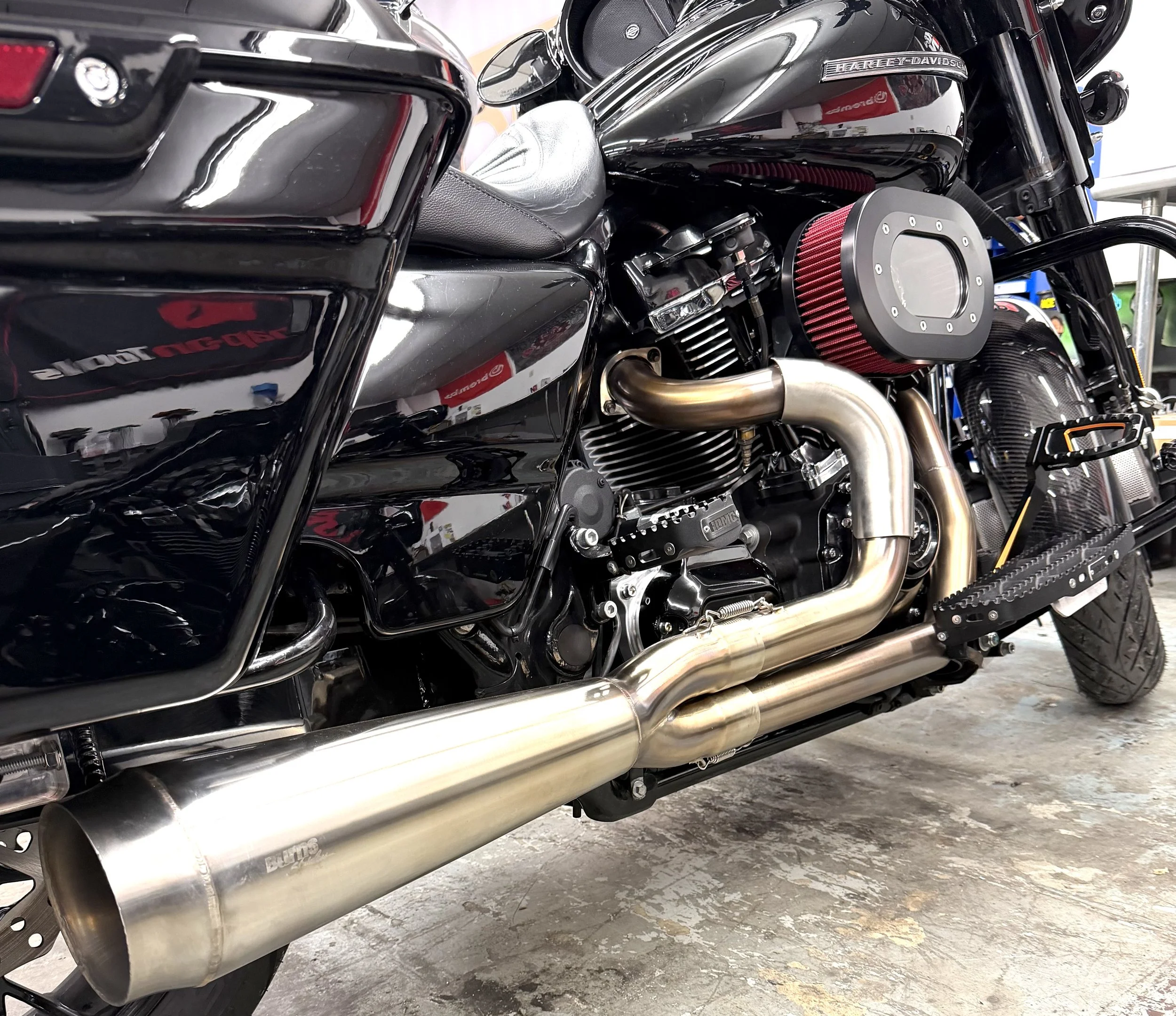 Close-up of a black motorcycle with chrome details, focusing on the engine, exhaust pipes, and seat.