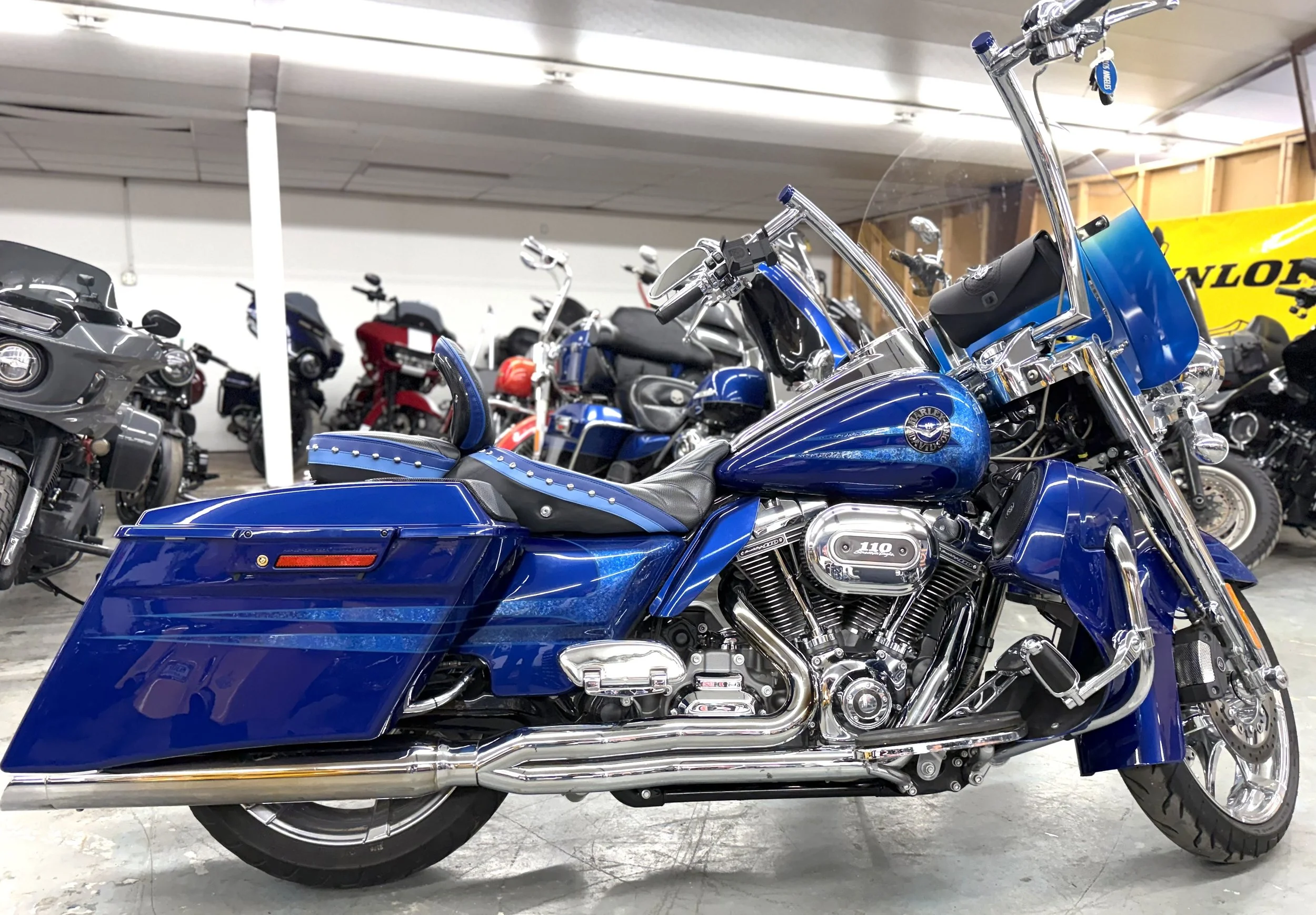 A blue Harley-Davidson motorcycle inside a showroom with other motorcycles in the background.