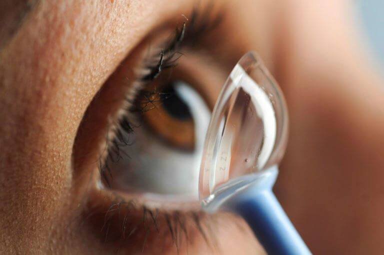 Close-up of a person's eye with a contact lens applicator near the eye.
